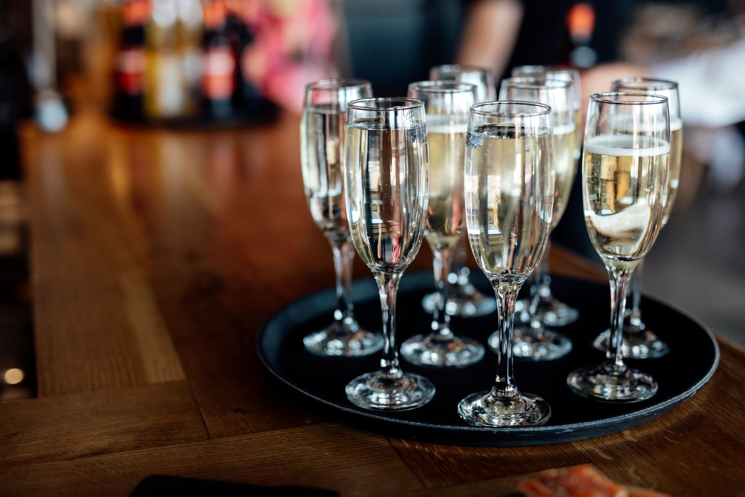 Champagne flutes filled with bubbly arranged on black serving tray at celebration.