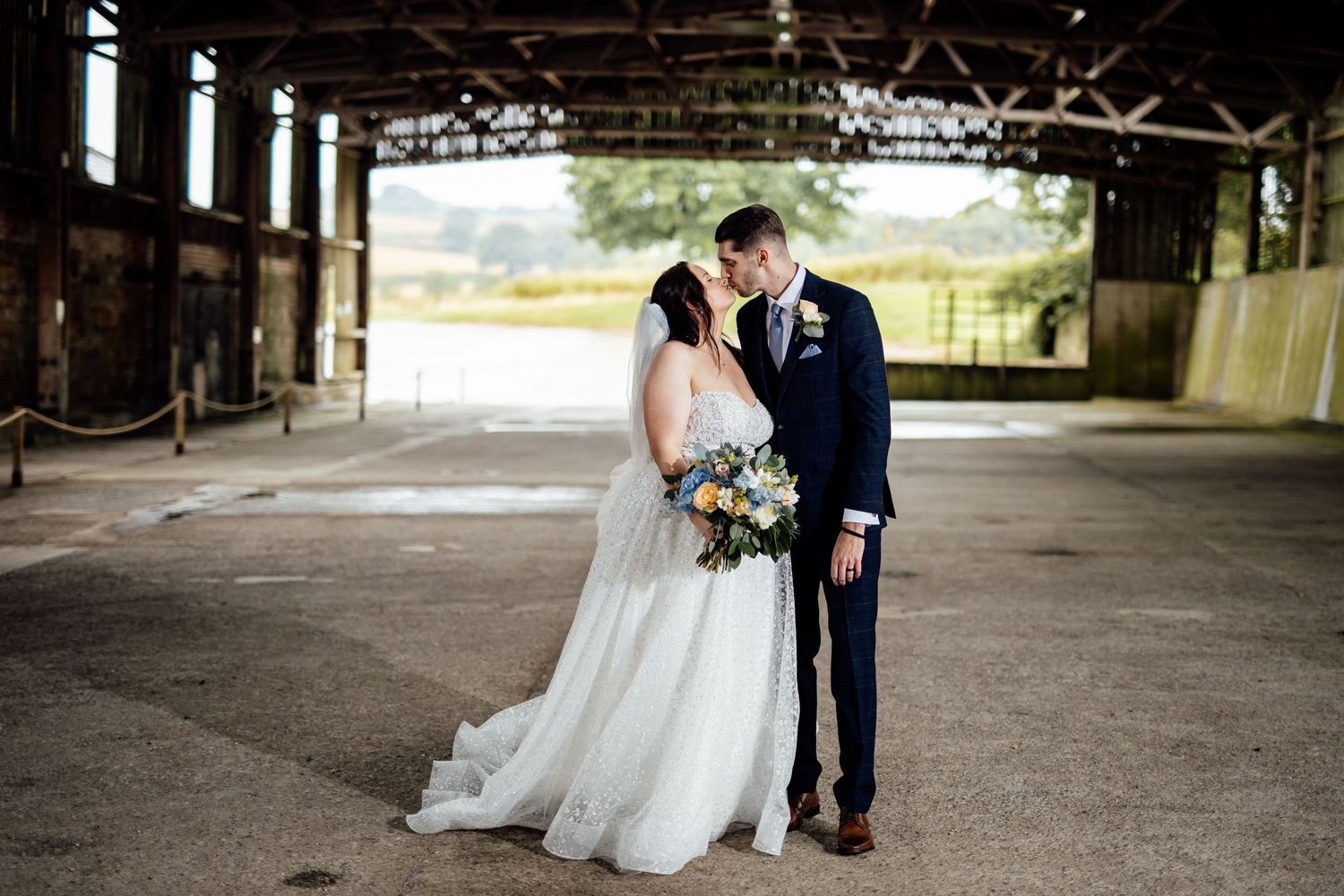 Wedding couple photographed in rustic industrial venue with natural lighting.