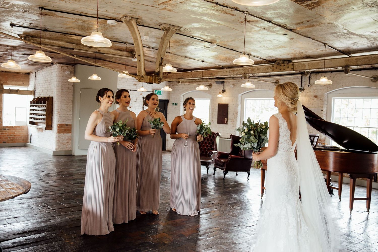 Wedding party gathered in a rustic indoor venue with exposed wooden beams and natural lighting.