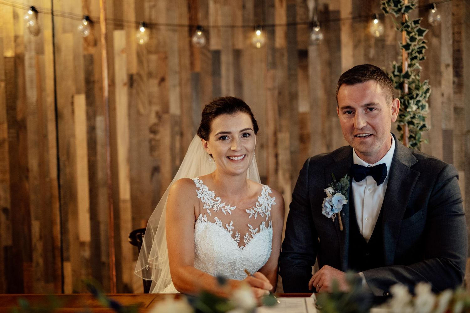 Candid moments during wedding reception against rustic wooden wall backdrop.