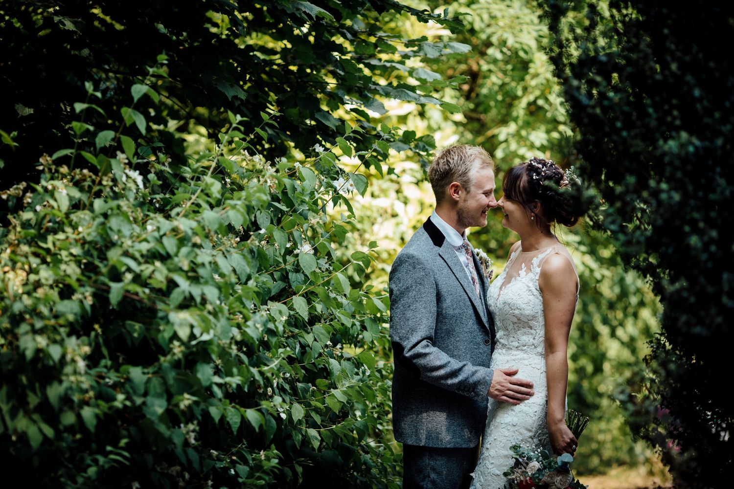 A romantic wedding couple shares an intimate moment in a lush garden setting.