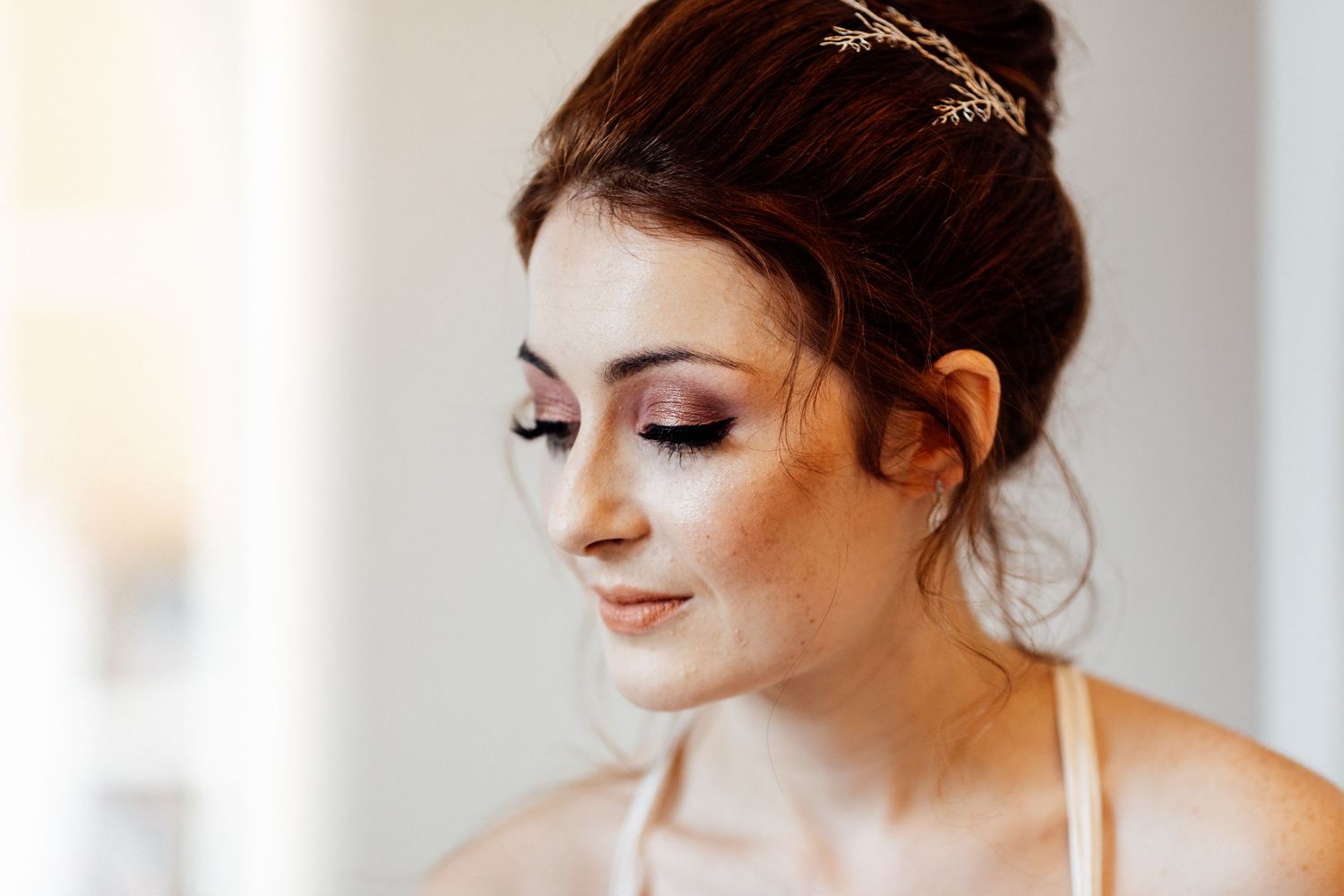 Elegant bridal makeup and updo hairstyle with delicate hair accessory.