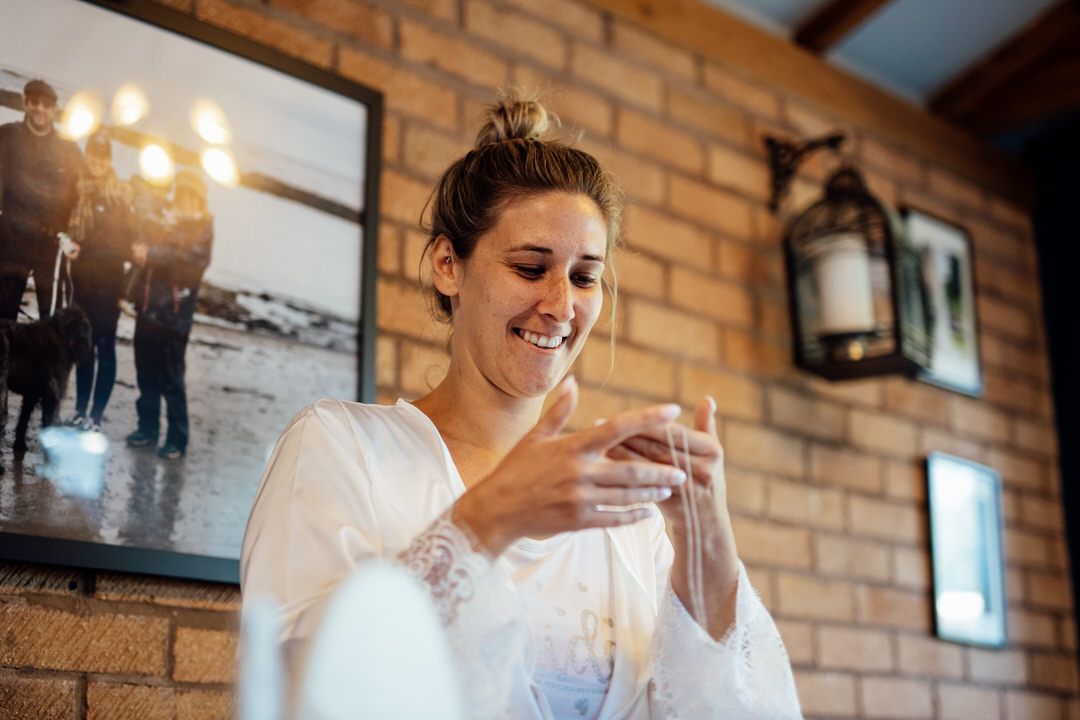 Candid laughter during bridal preparations in brick-walled venue.