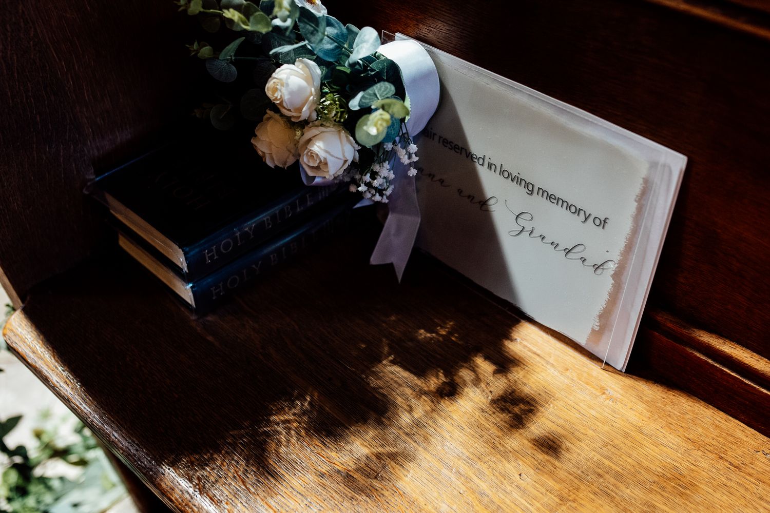 Wedding details with flowers and guest book on wooden surface in natural light.