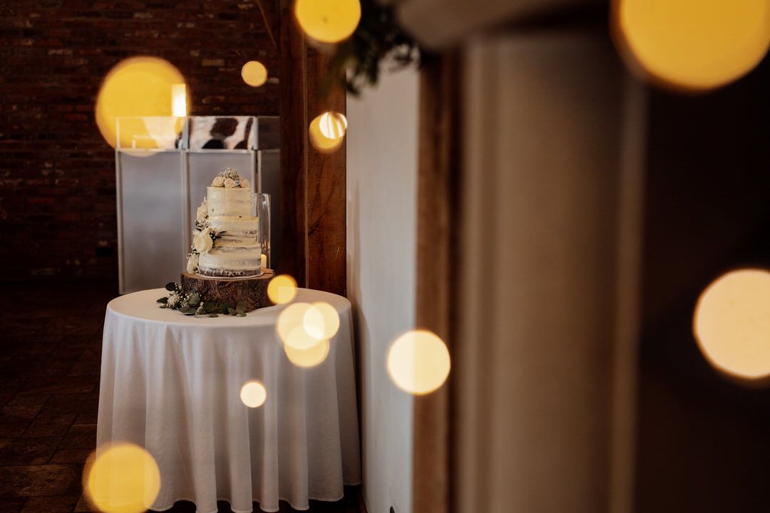 Wedding cake display with bokeh lights and exposed brick wall background.
