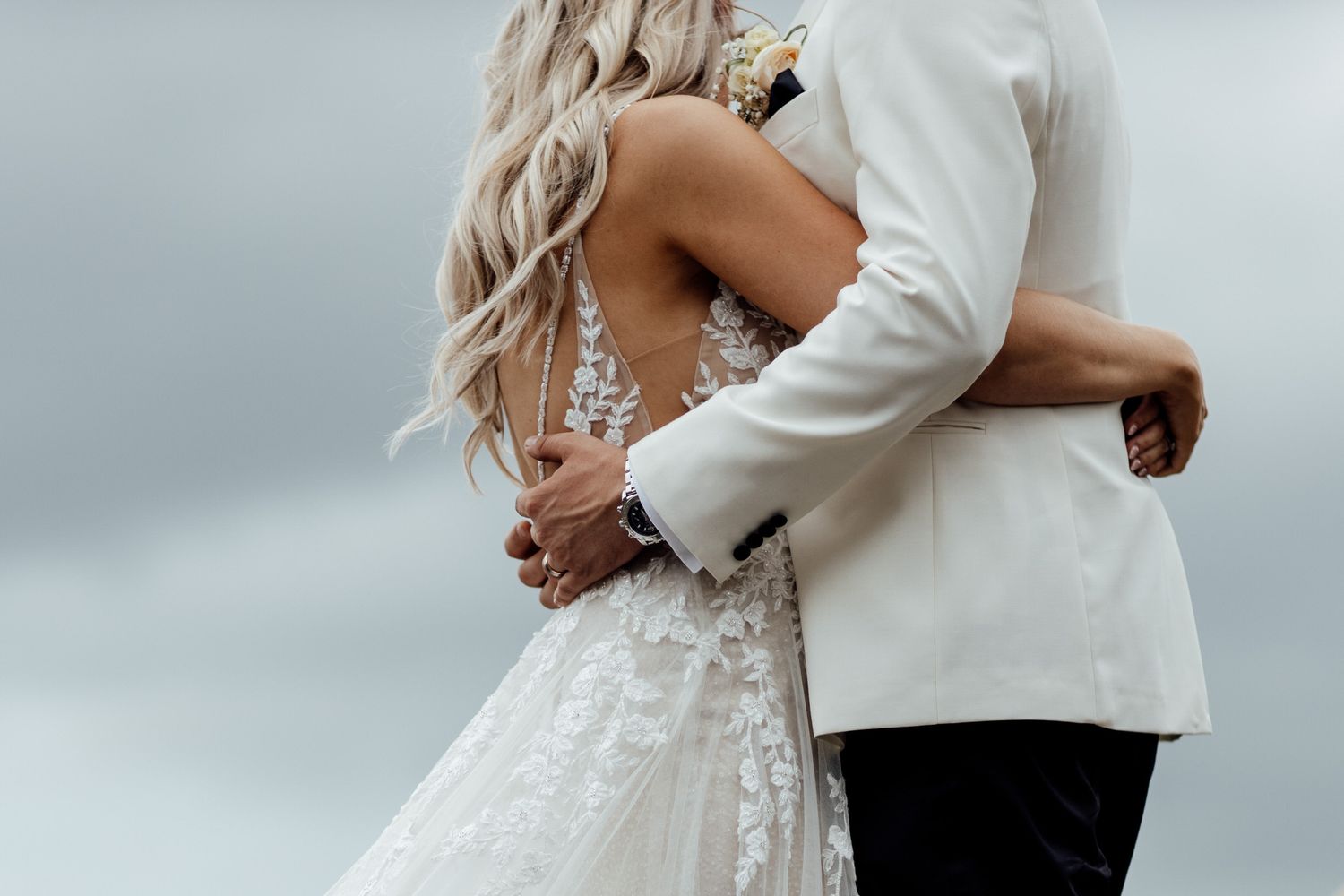Elegant wedding couple embraces while dancing together in romantic outdoor setting.