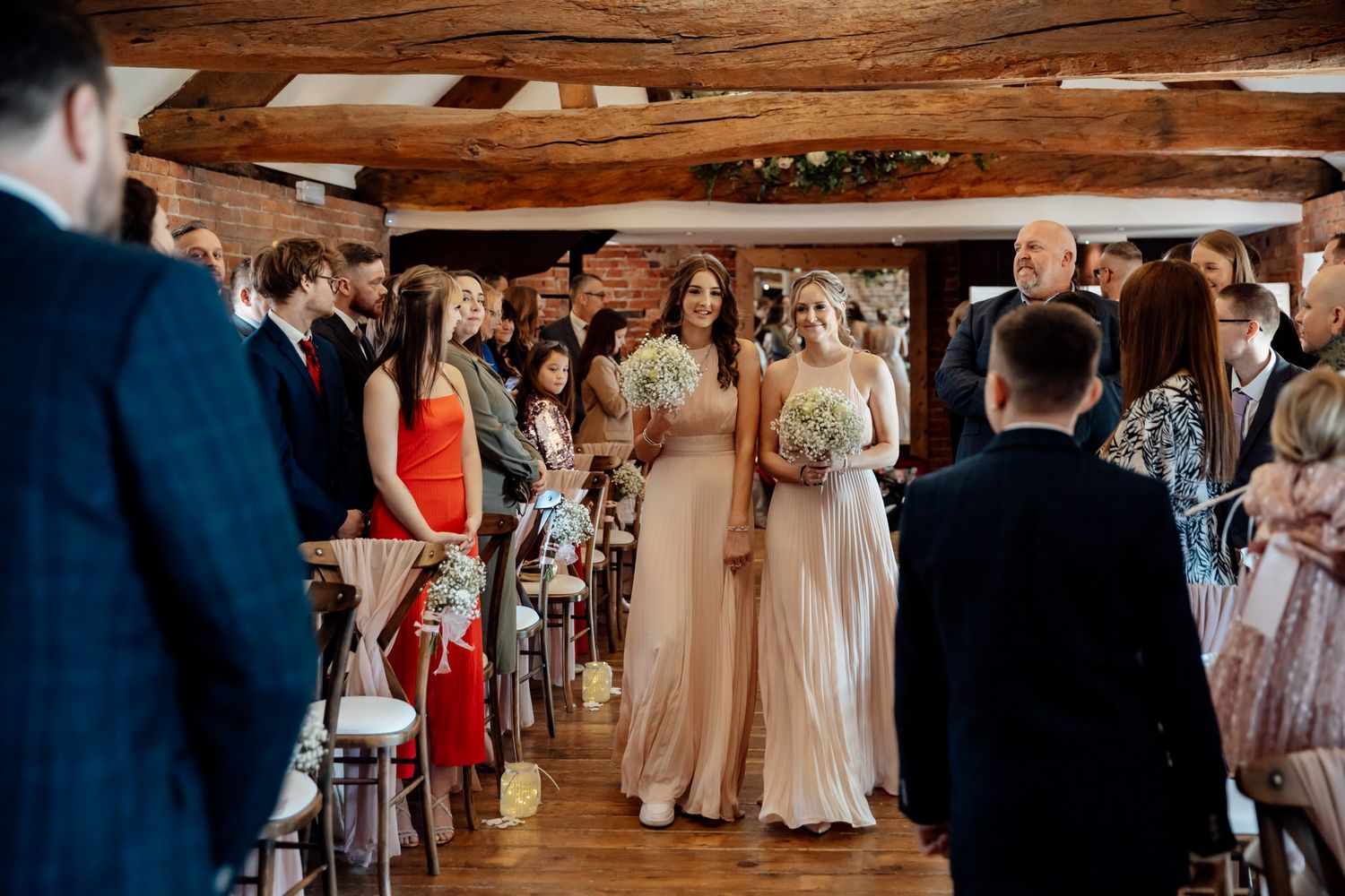 Wedding reception setup in rustic barn with wooden beams and elegant table settings.