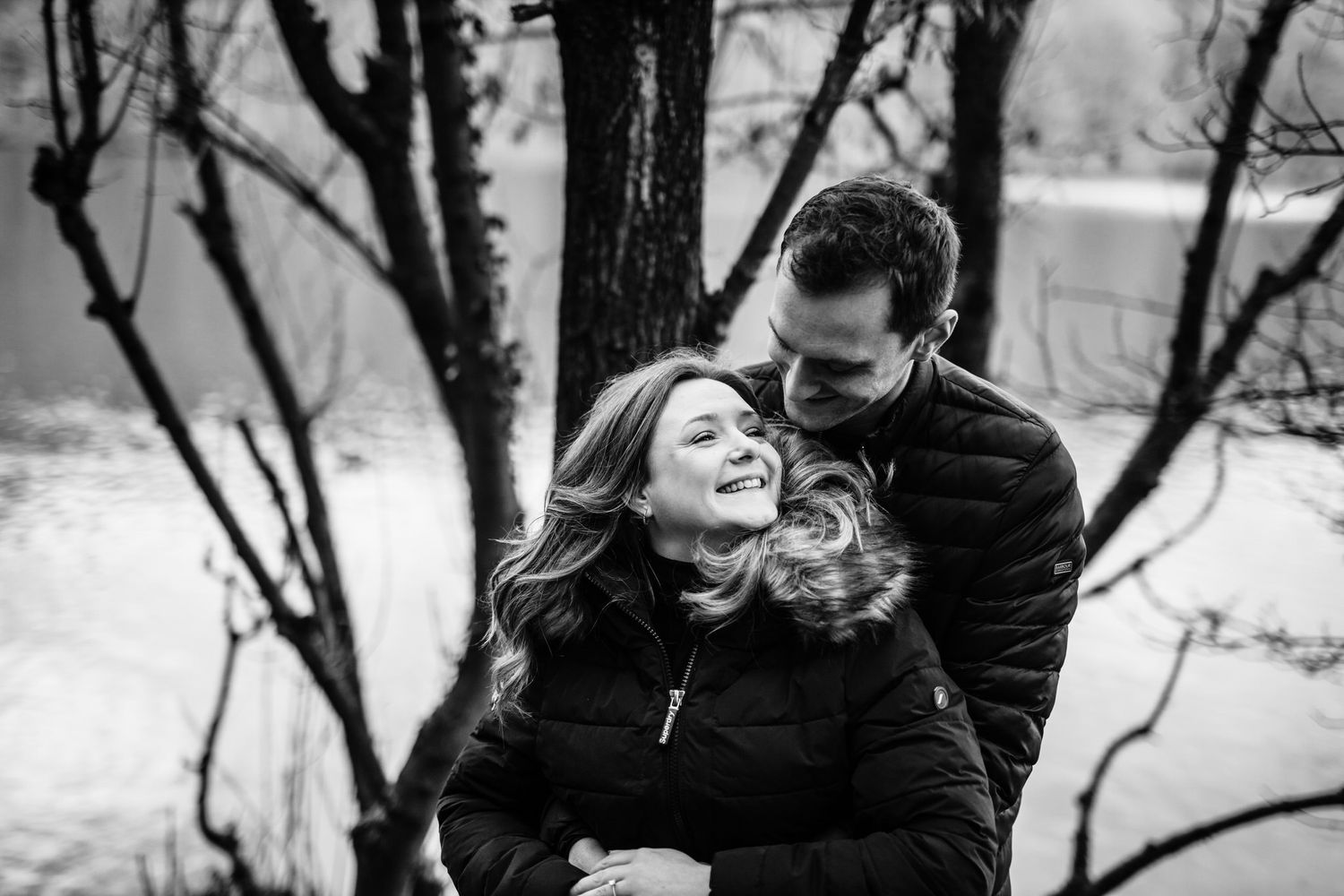Winter engagement photoshoot among bare trees in black and white.