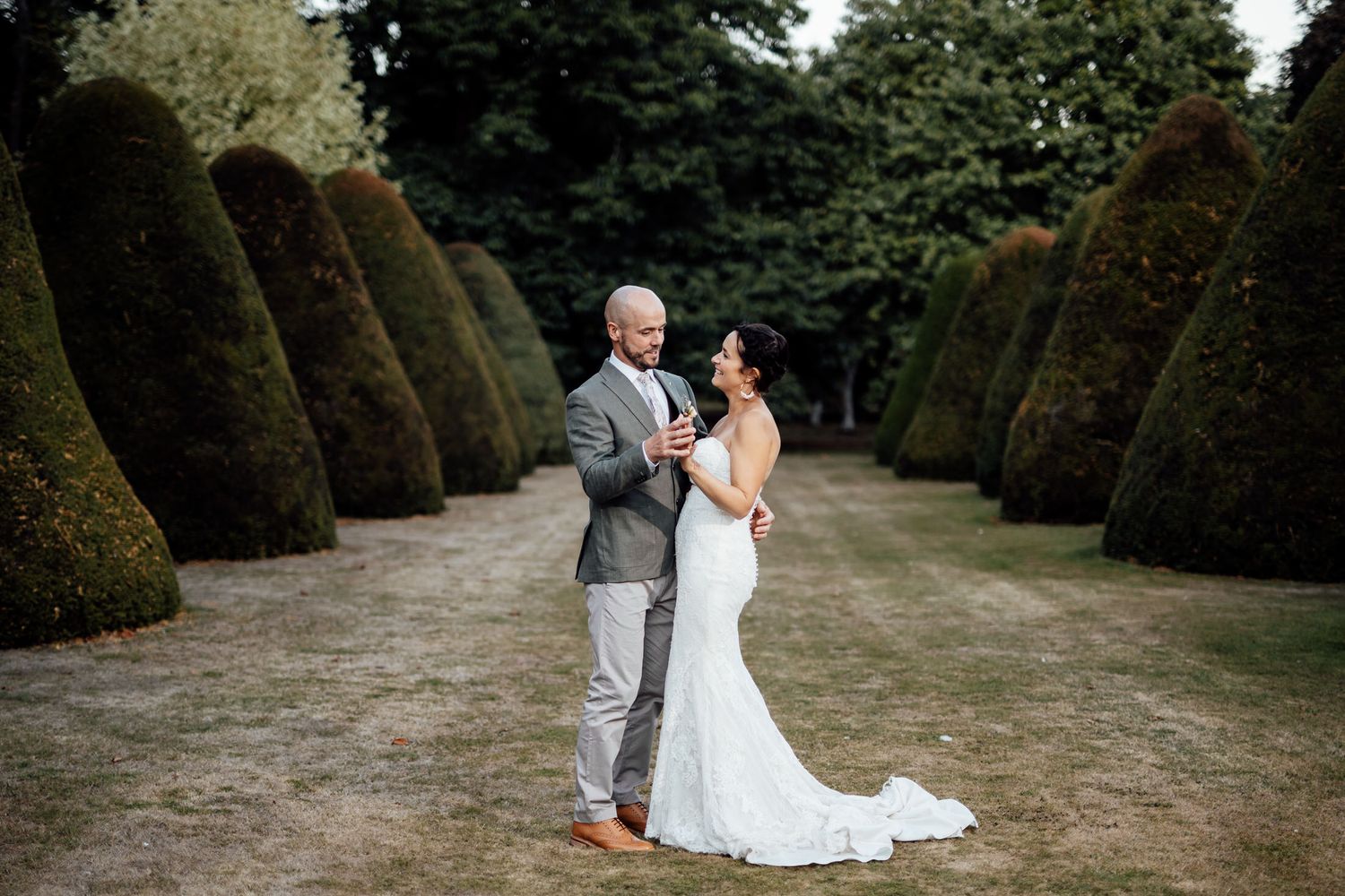 Romantic wedding photography session in a formal garden with manicured hedges.
