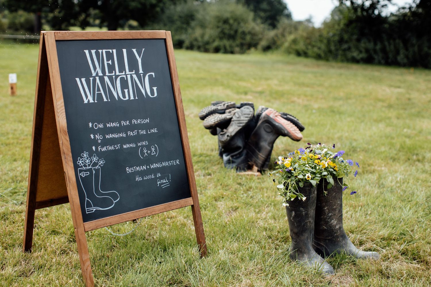 Rustic chalkboard wedding signs displayed on wooden A-frames outdoors.