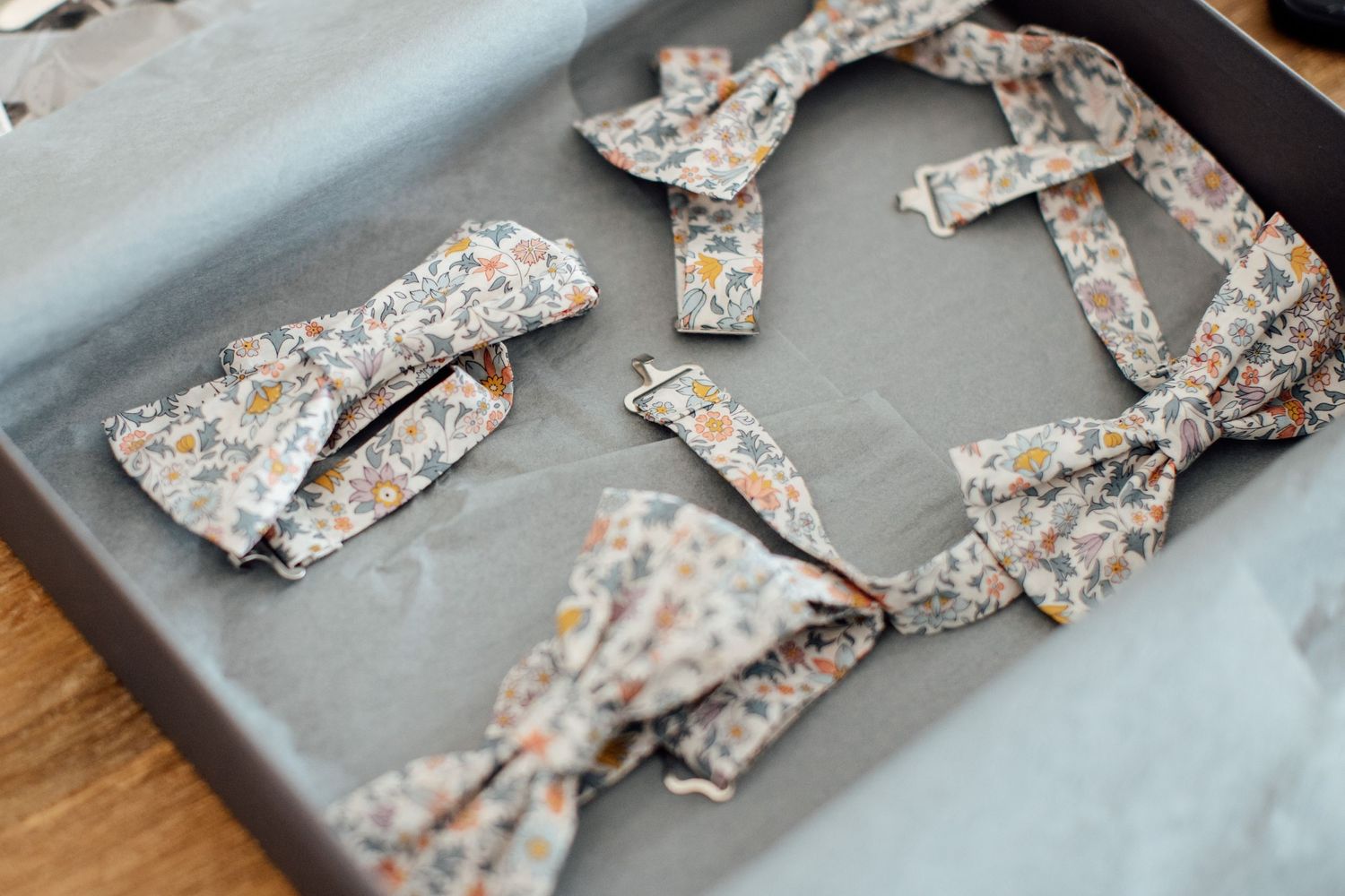 Floral patterned bow ties arranged on a gray surface for wedding preparation.