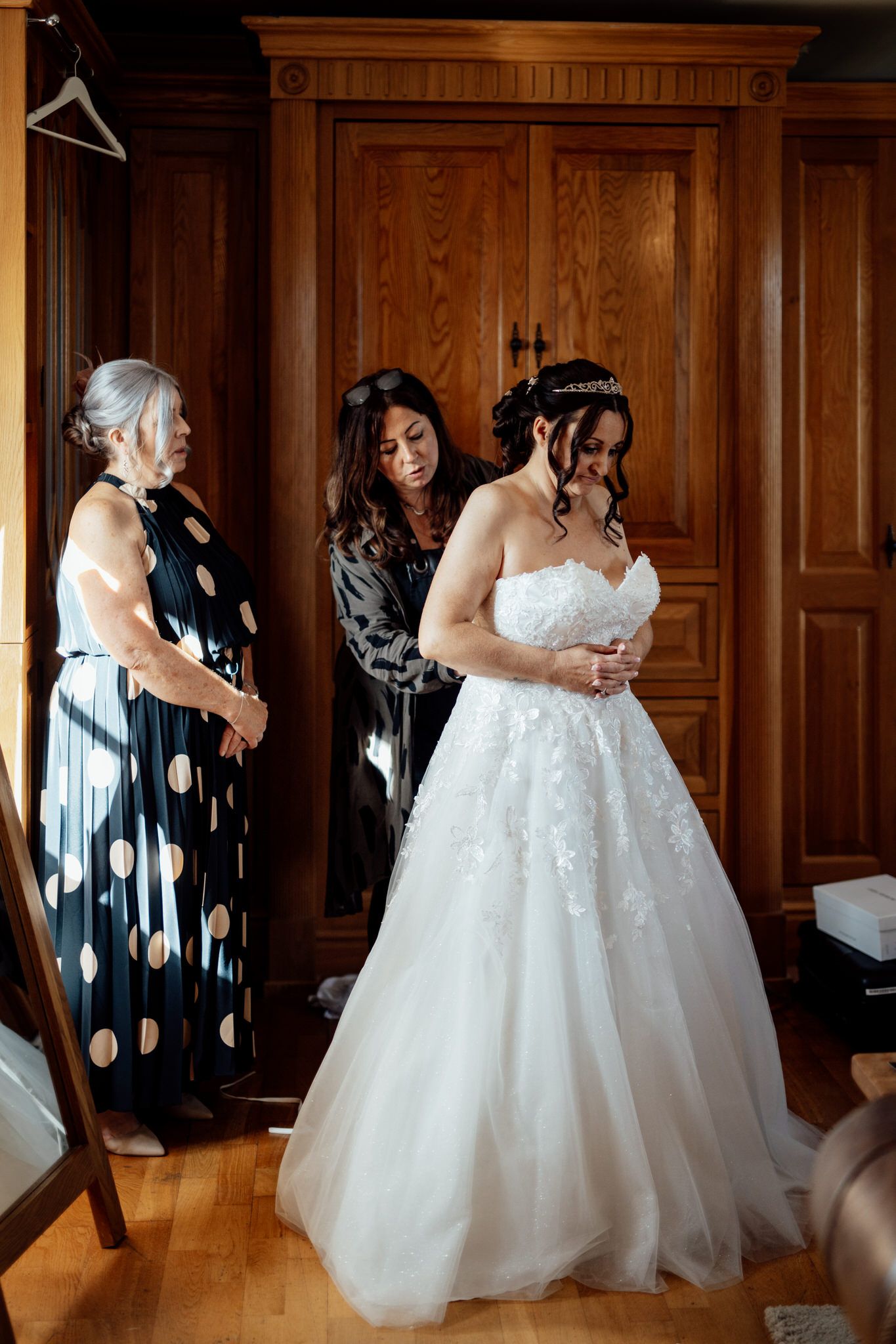 Wedding party preparing in an elegant wood-paneled room with polka dot dresses.