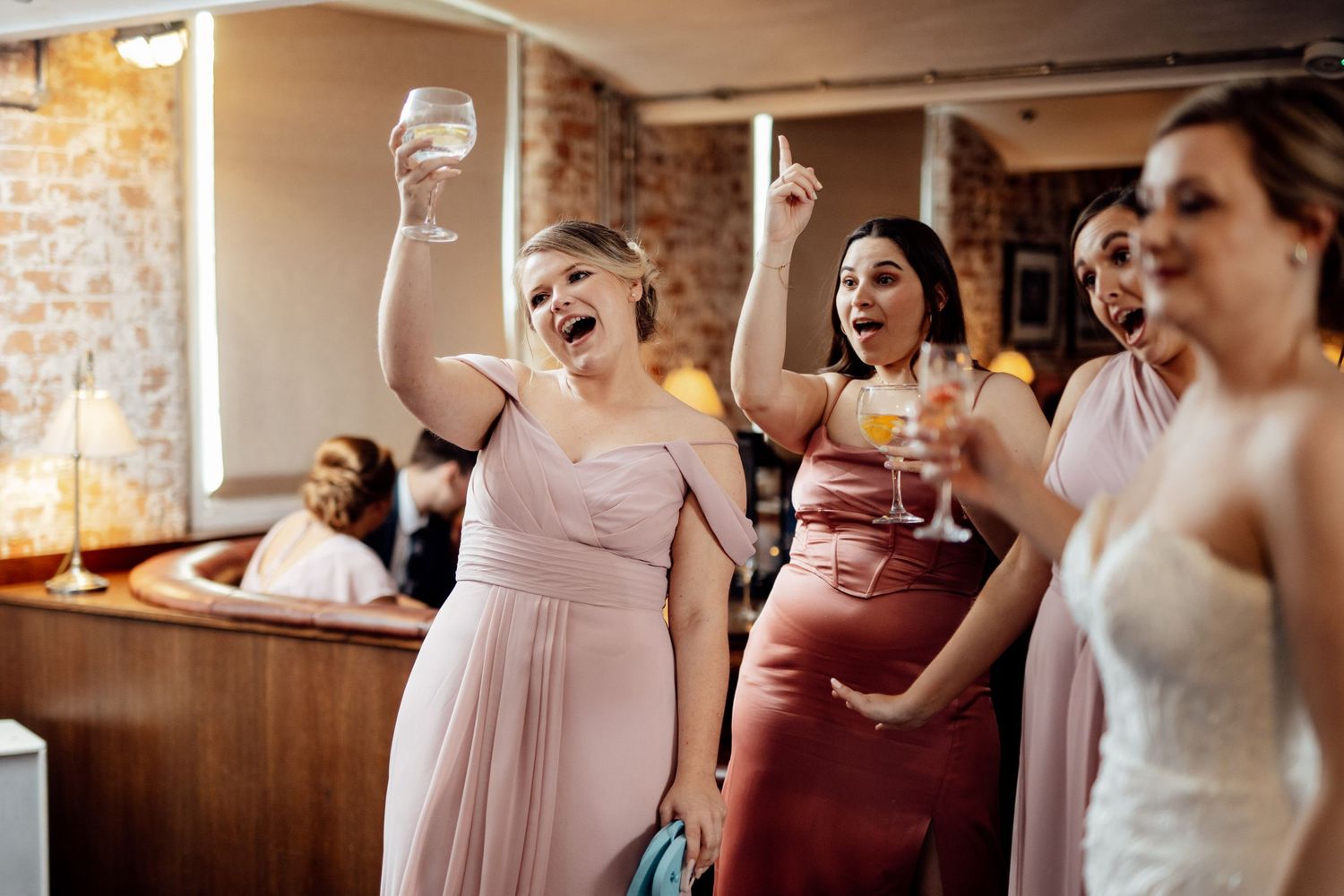 Wedding guests celebrating enthusiastically at a reception with drinks raised.