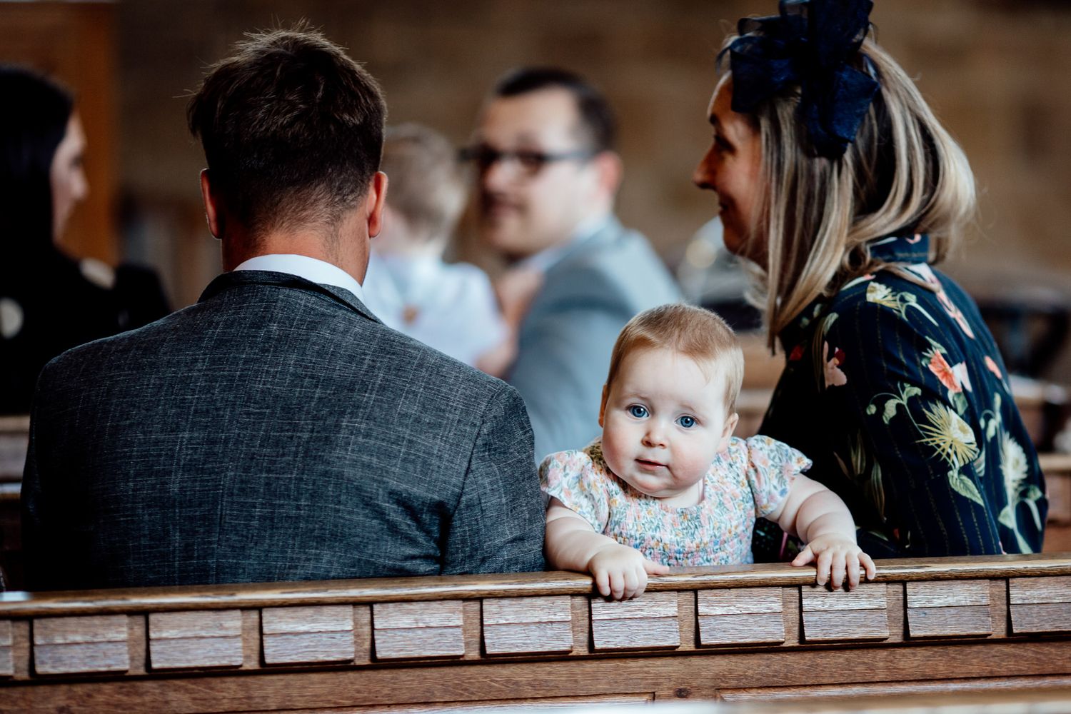 Wedding guests seated at rustic wooden tables during an indoor reception.