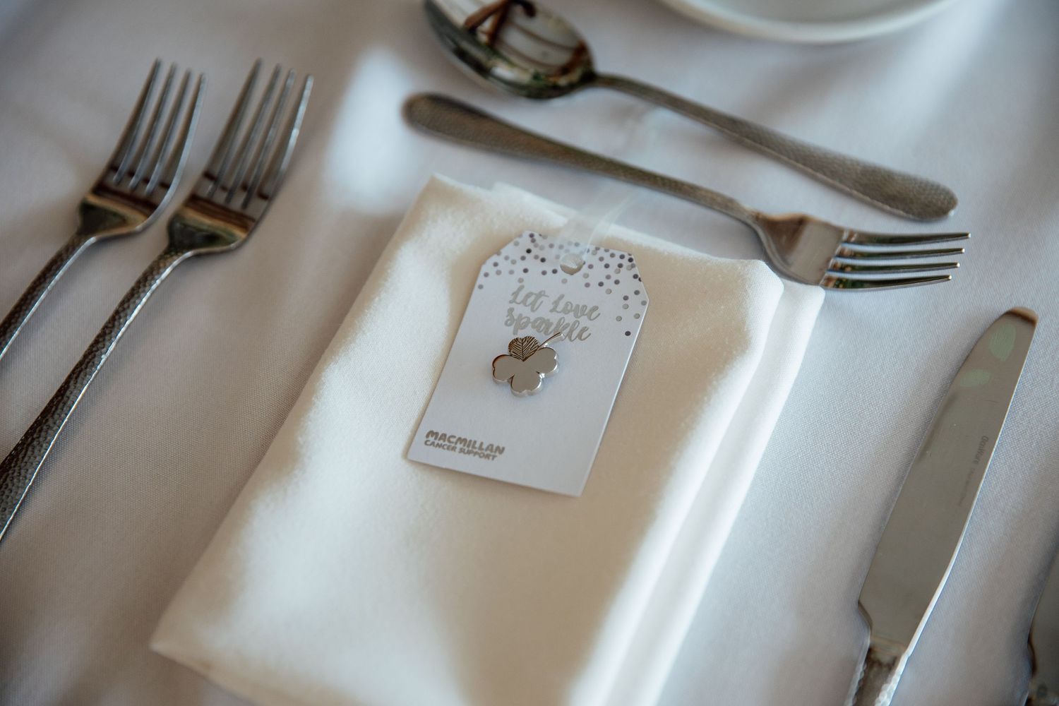 Elegant place settings with white plates and silverware at a wedding reception.