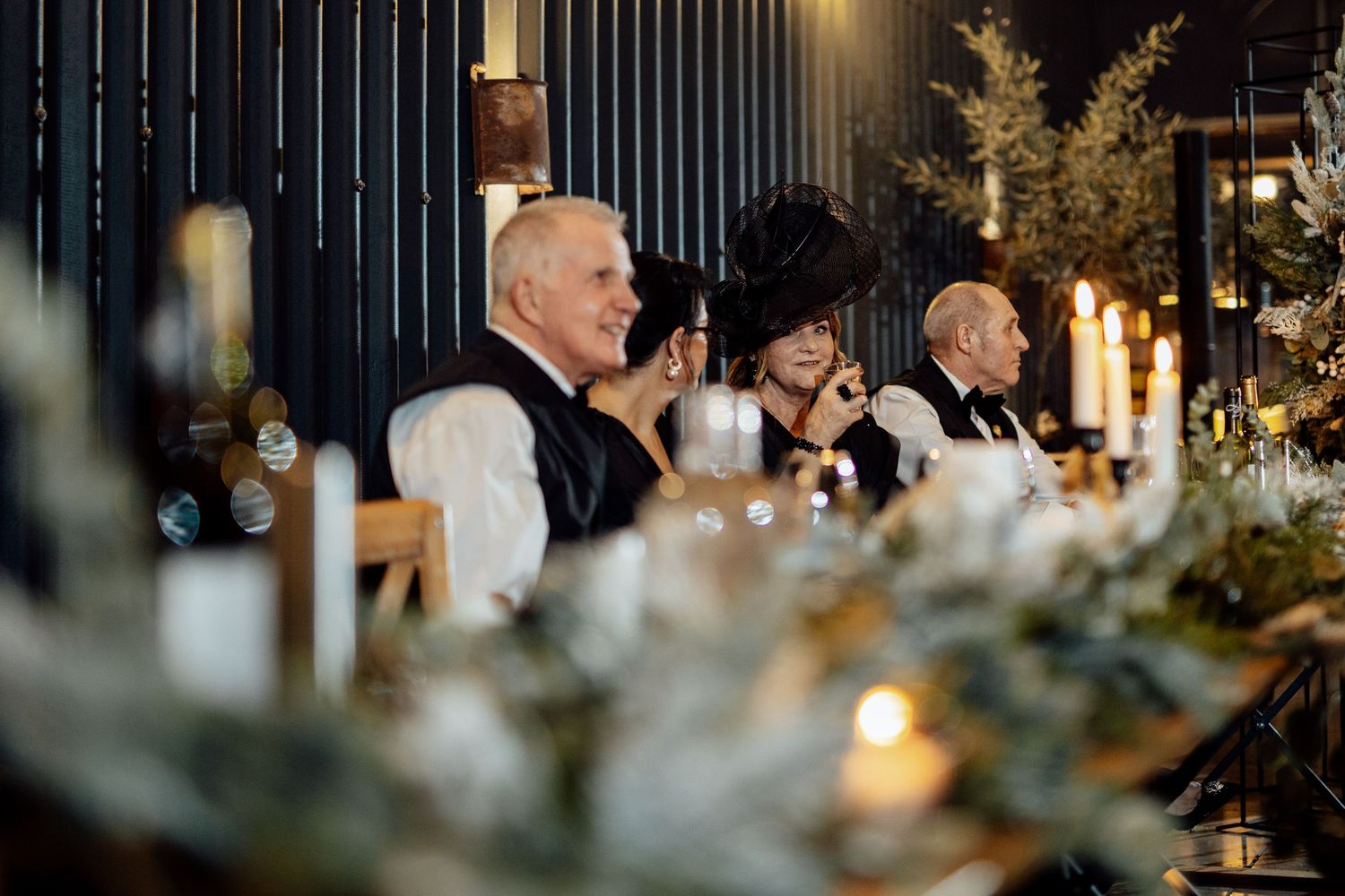 Elegant wedding reception table setting with candlelight and greenery decorations.