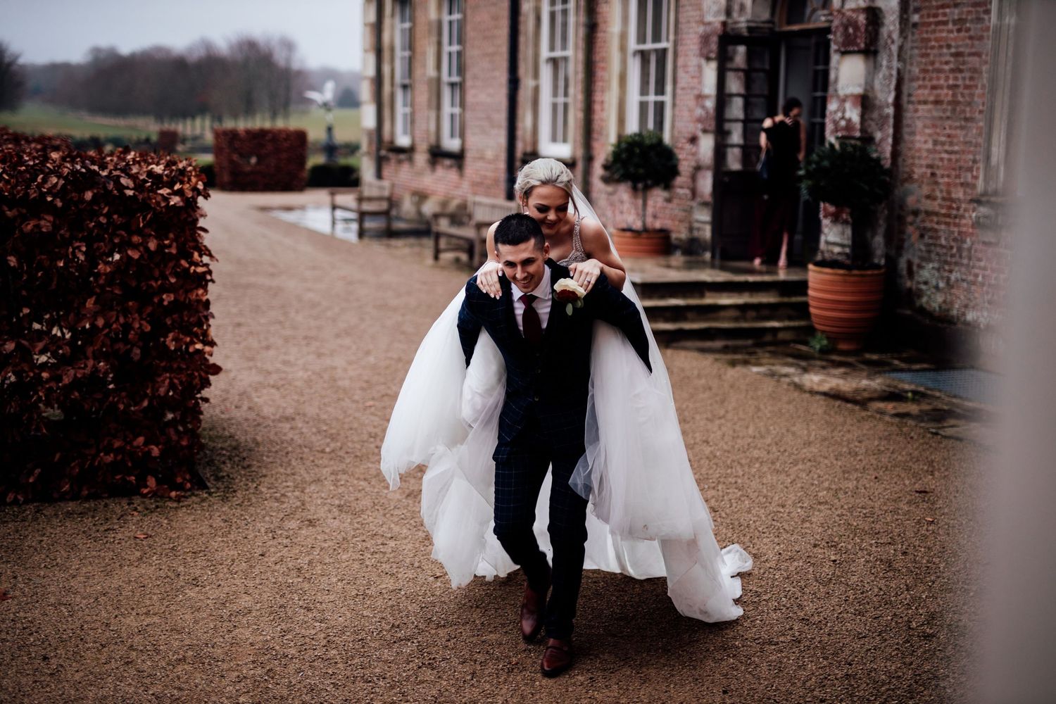 Couple walking along gravel path outside historic brick building.