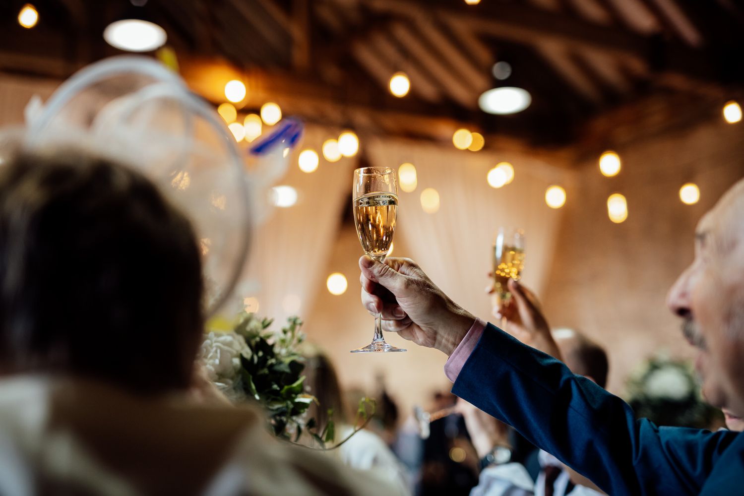 Guests mingling at a rustic wedding venue with exposed brick walls and overhead string lights.