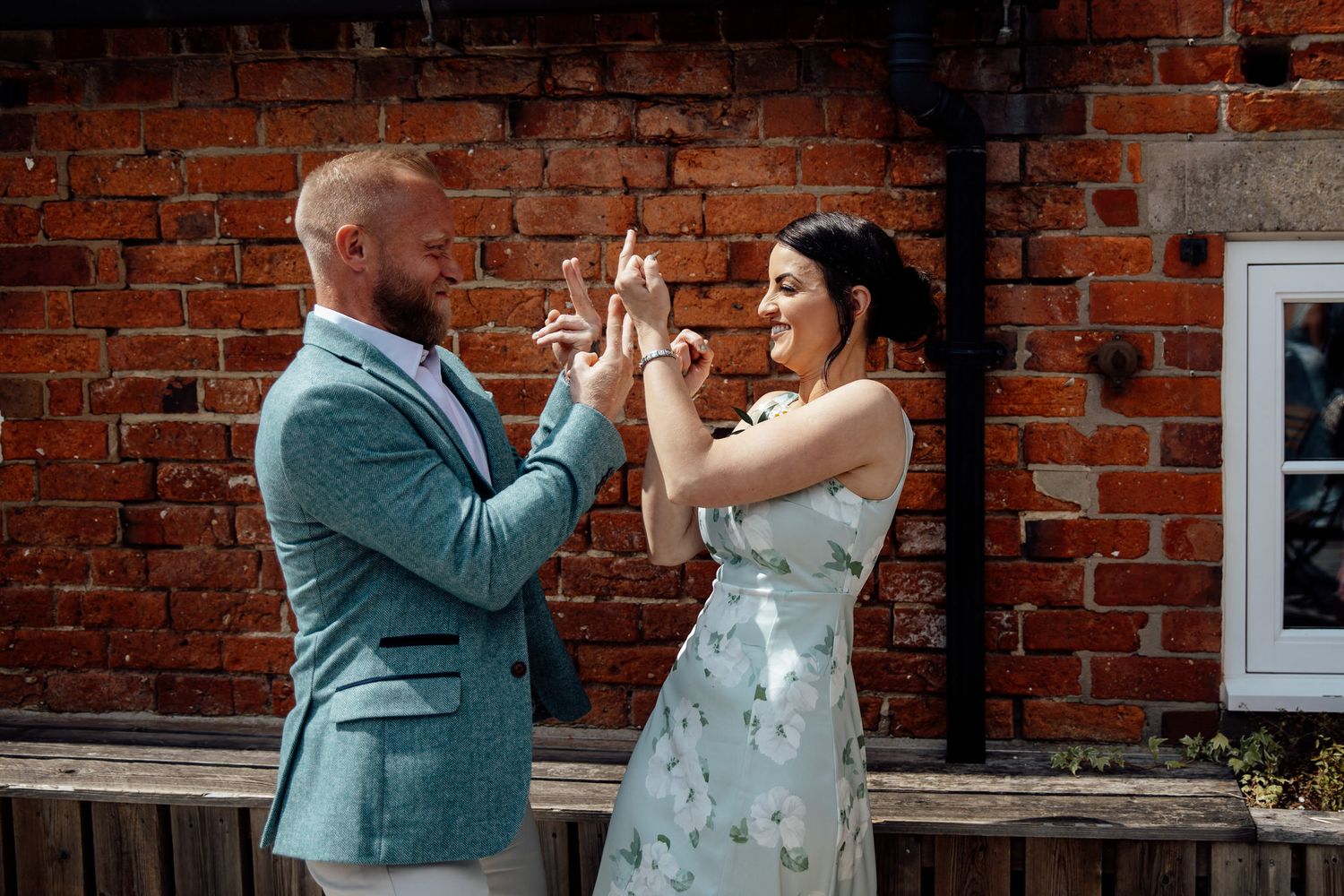 A couple sharing a romantic moment against a red brick wall background.