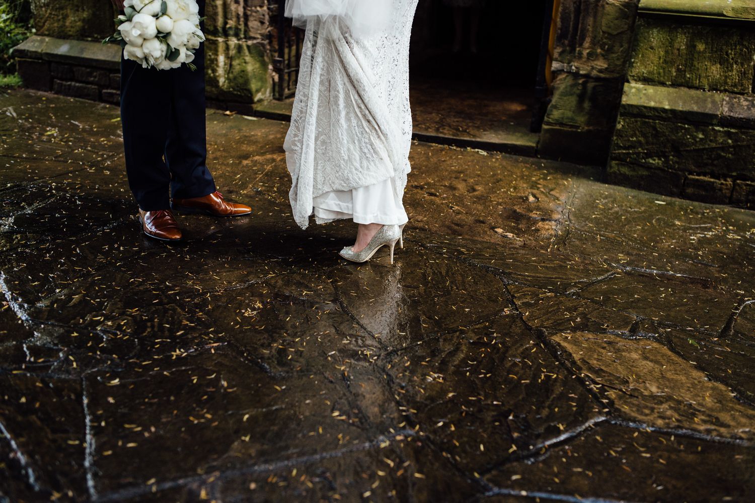Newlyweds walking together on stone pathway surrounded by greenery.