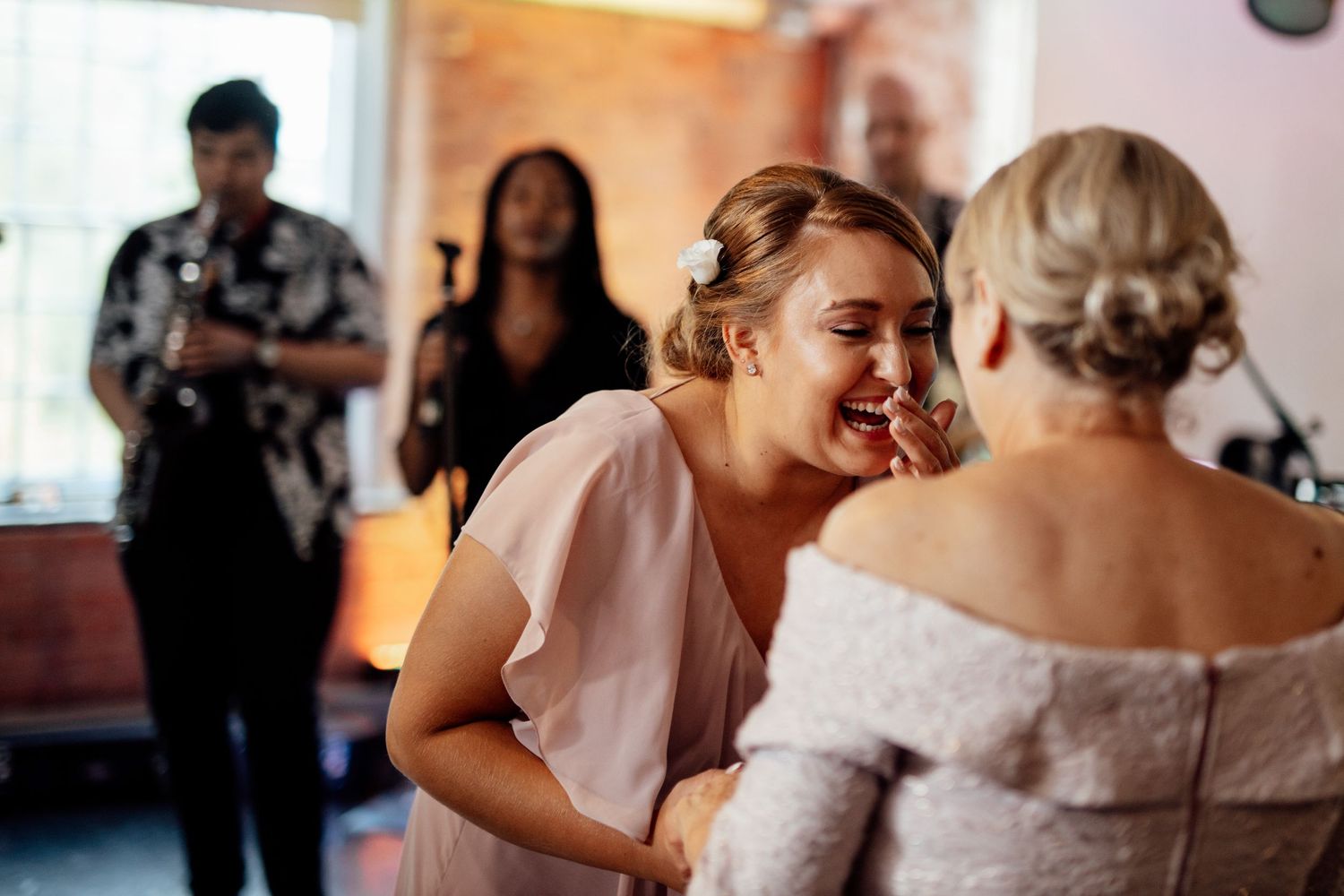 Wedding party members in blush pink dresses preparing for the ceremony.