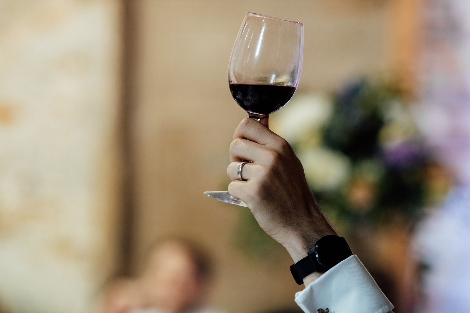 Wine glasses held up during wedding toasts in an elegant reception setting.
