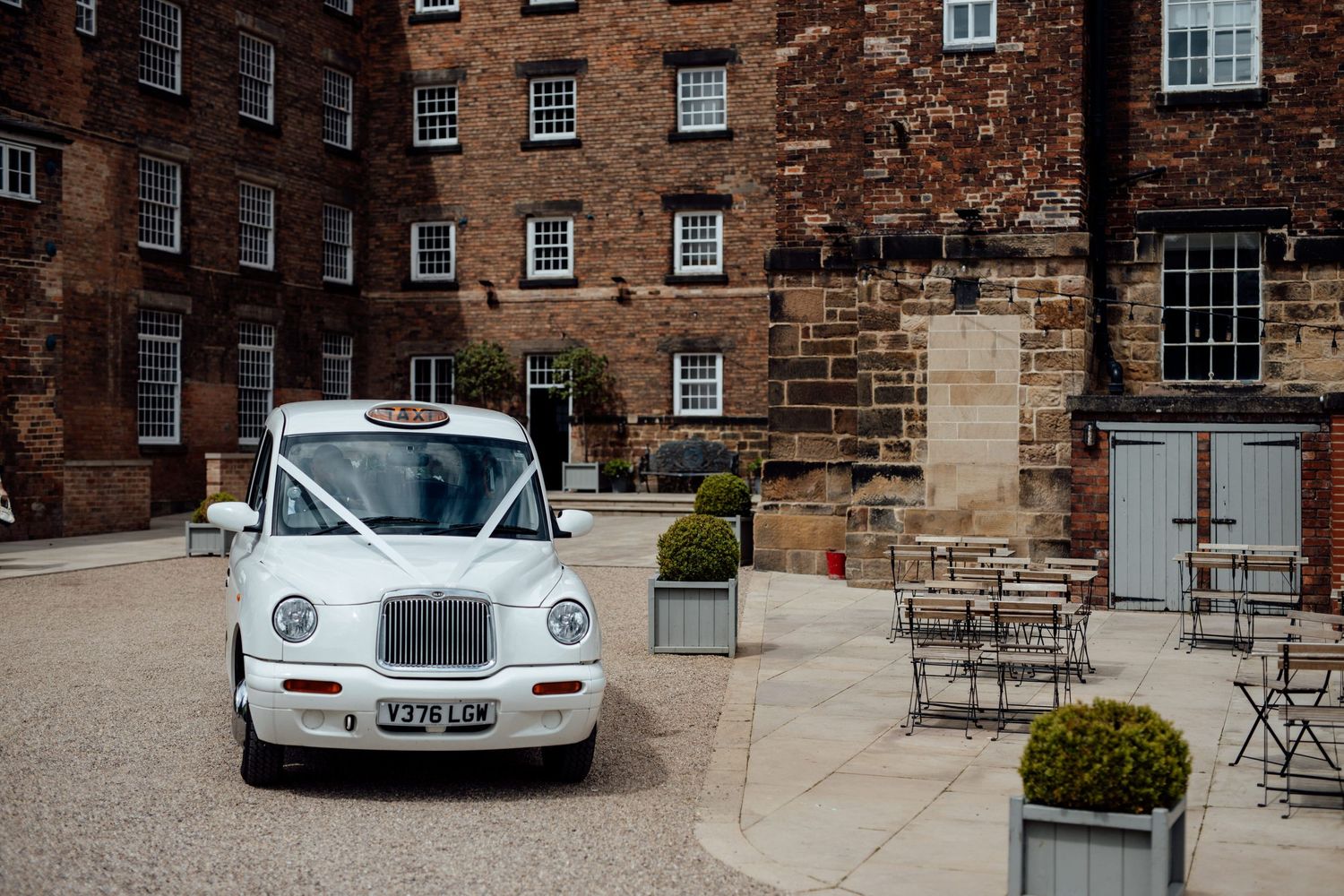 Classic cars parked outside a historic brick building with stone architecture.