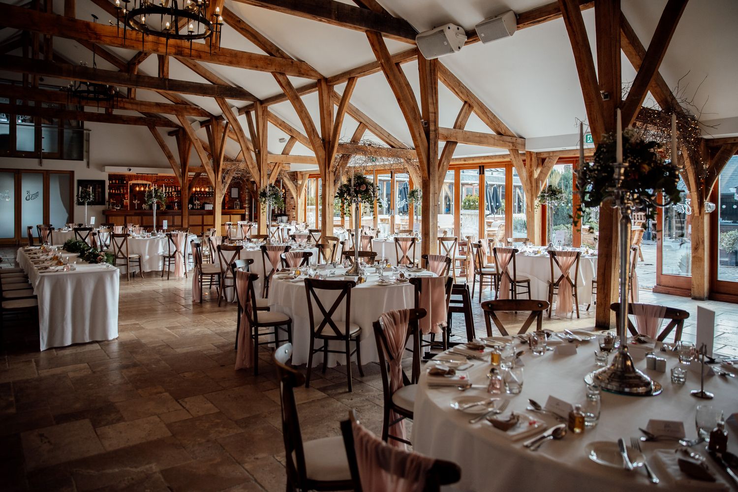 Wedding reception tables set up in elegant barn venue with exposed wooden beams.