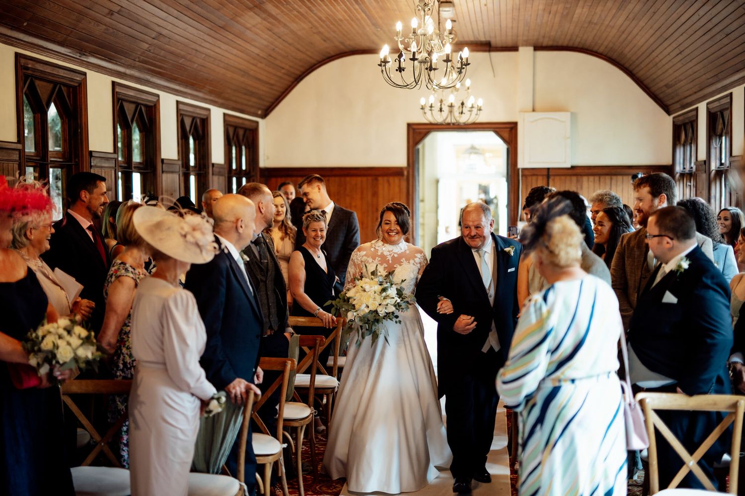 Wedding ceremony in a rustic chapel with wooden ceiling and chandelier.