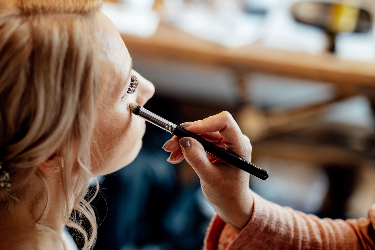 Professional makeup artist applying cosmetics during wedding day preparation.