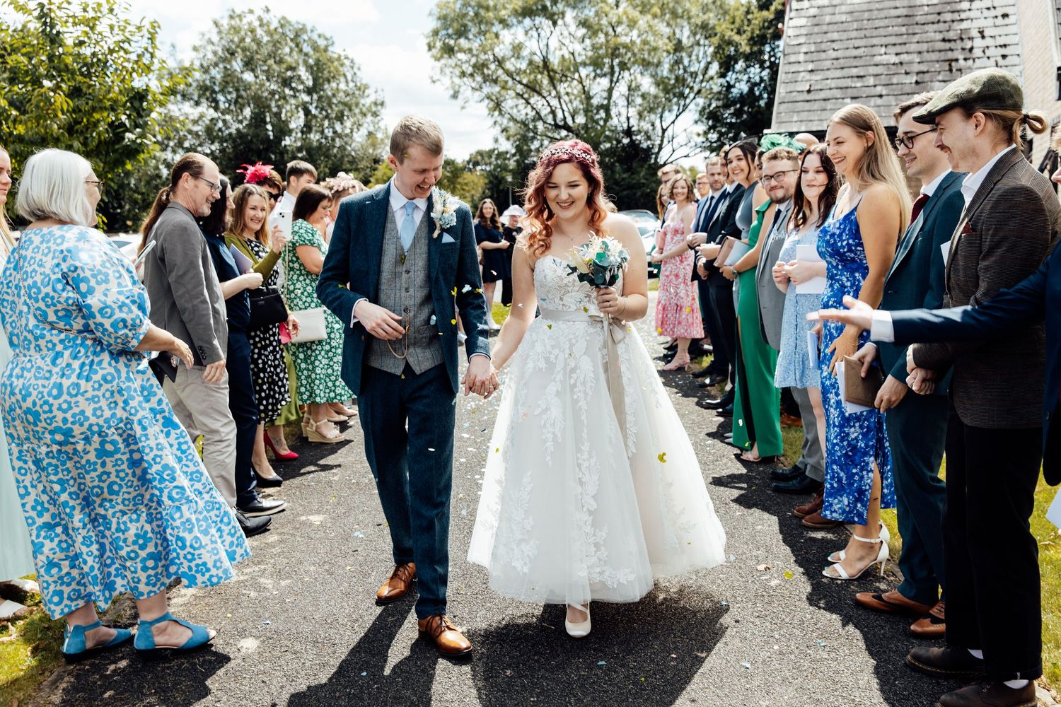 Wedding party and guests celebrating outdoors on a sunny day.