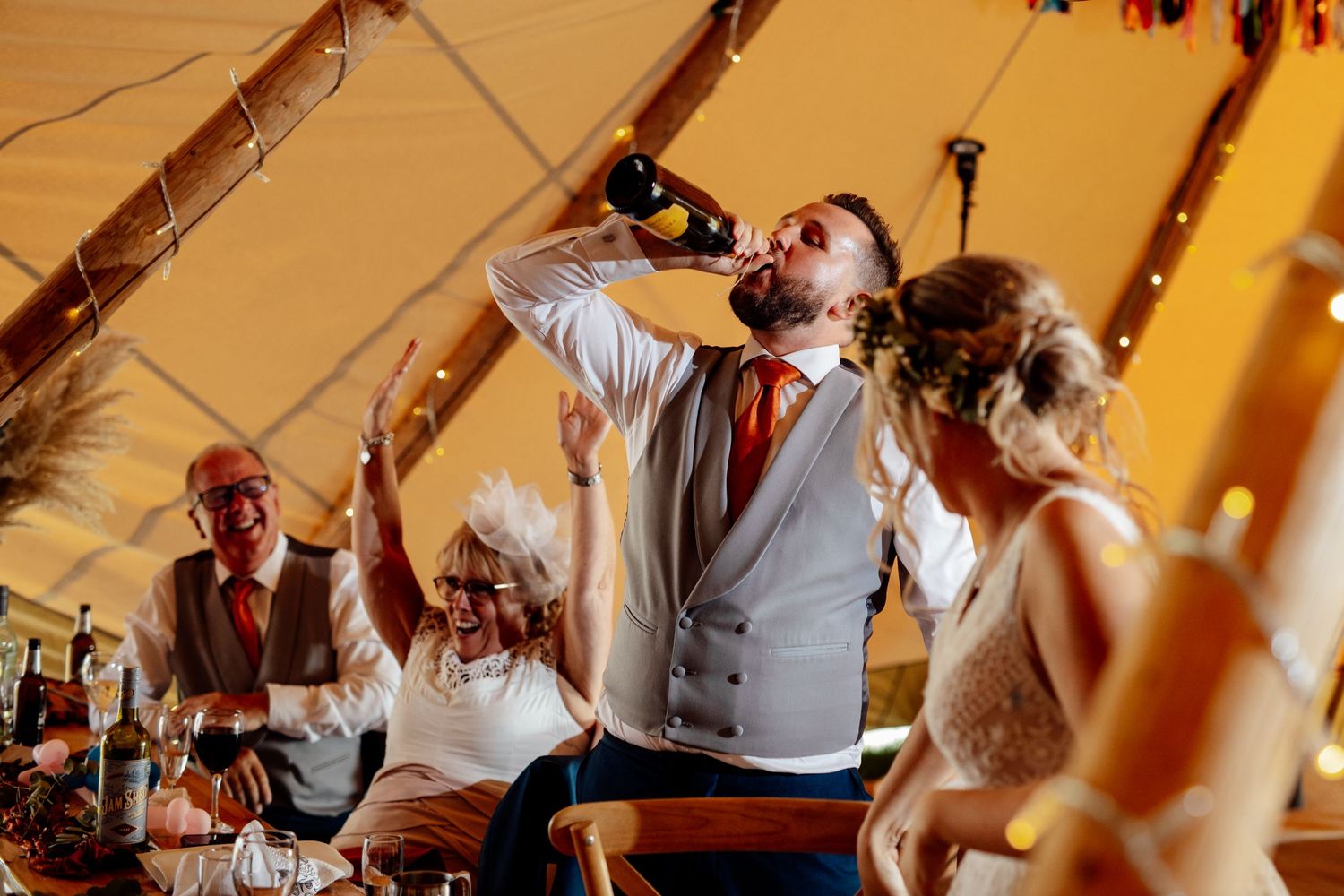 Wedding celebration under a tent with guests dancing and enjoying festivities.