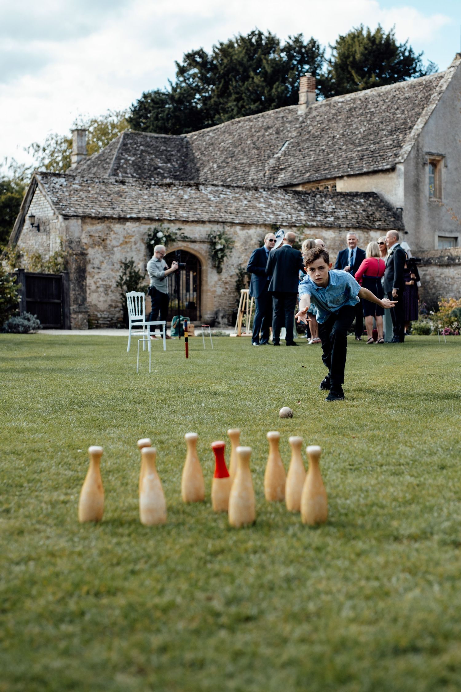 Wedding guests playing lawn games outside rustic stone cottage venue.