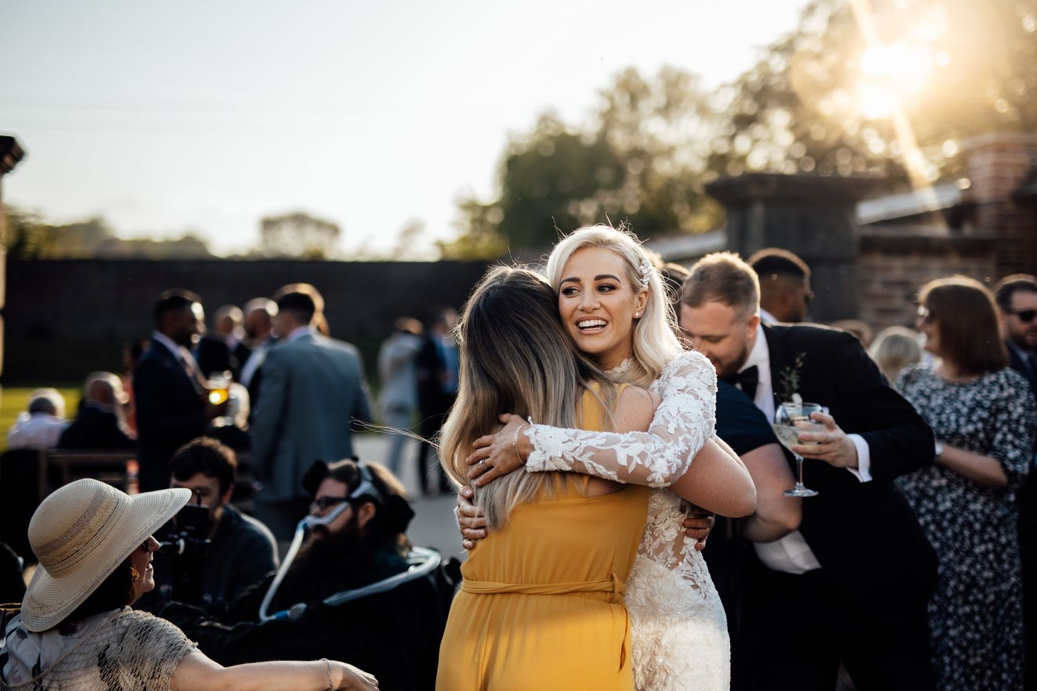 Wedding guests celebrate during an outdoor sunset reception with joyful expressions and warm lighting.