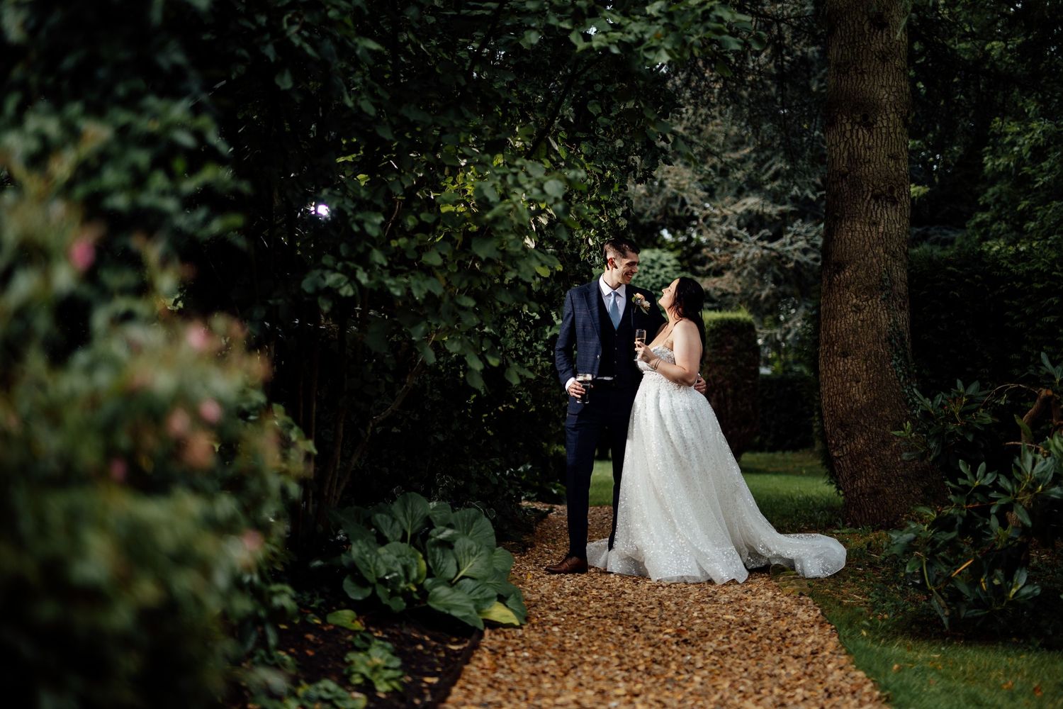 Romantic wedding photos captured in wooded garden setting with natural lighting.
