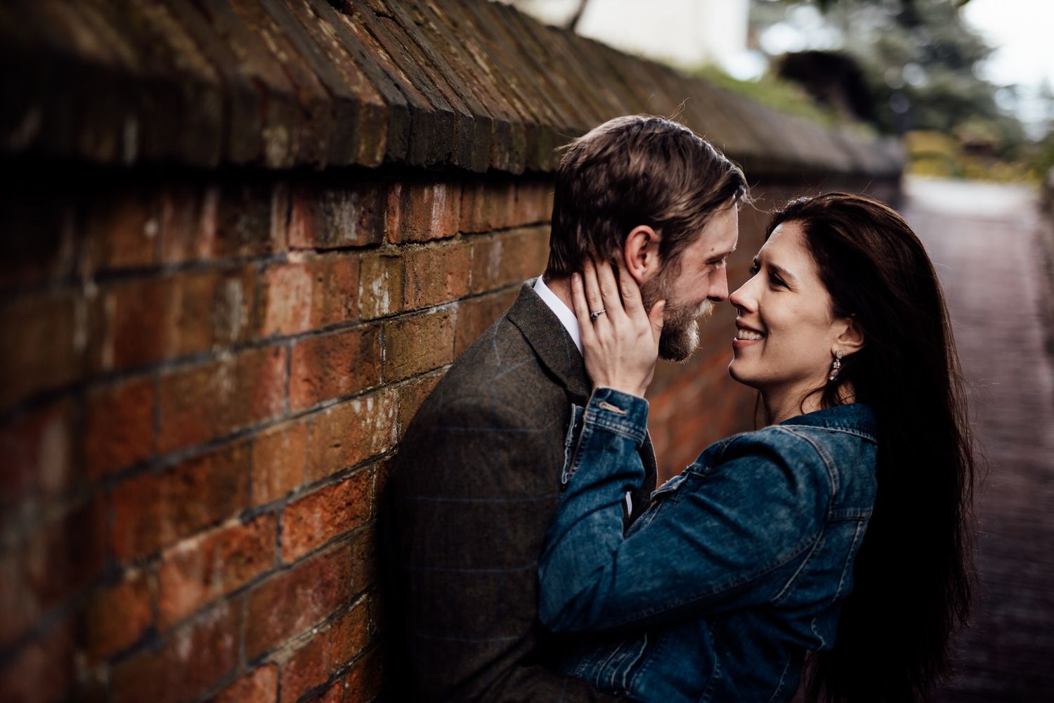 An intimate moment shared between two people against a rustic brick wall.