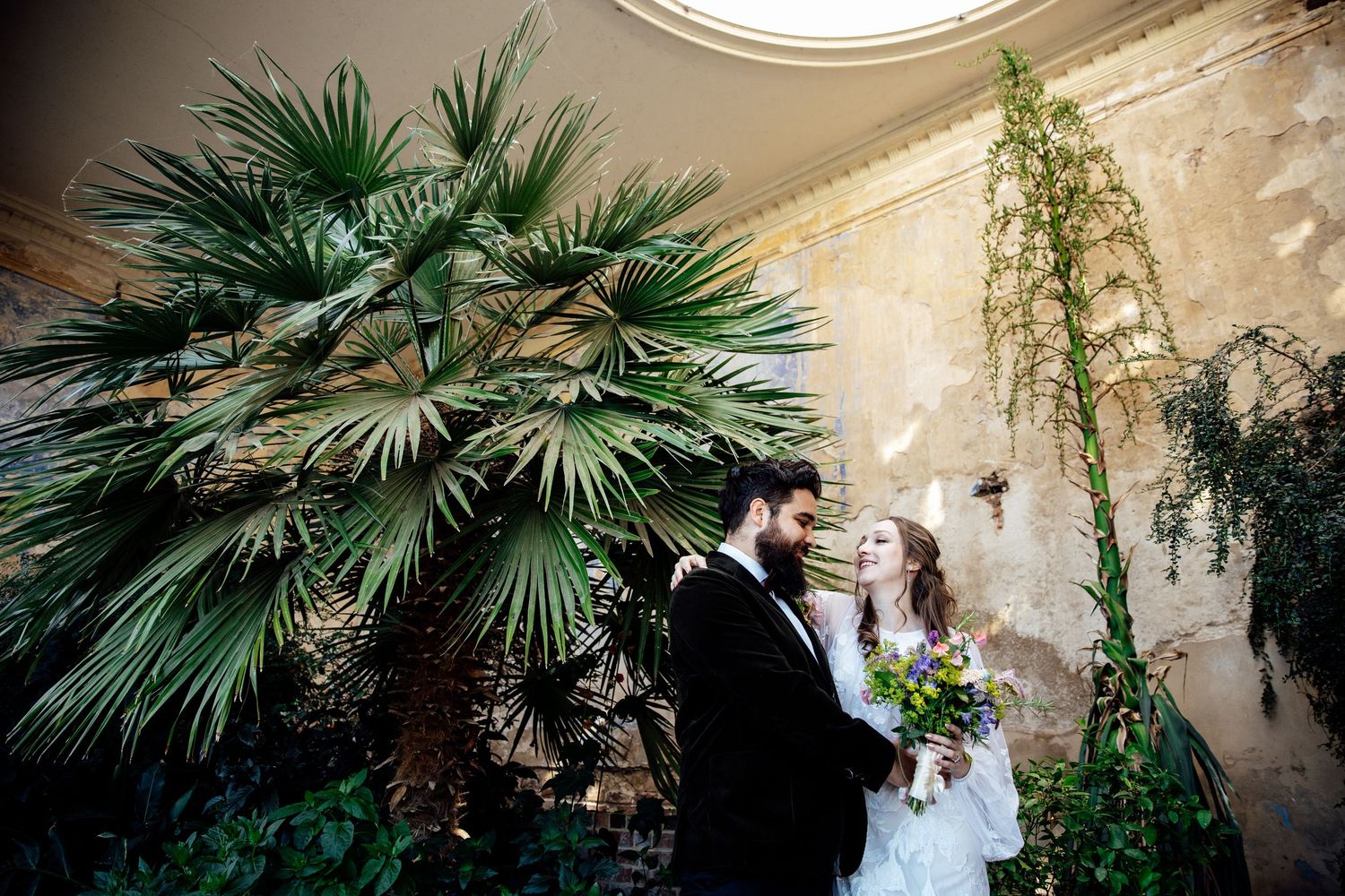 Palm fronds create a lush tropical backdrop for a romantic wedding scene at an elegant venue.