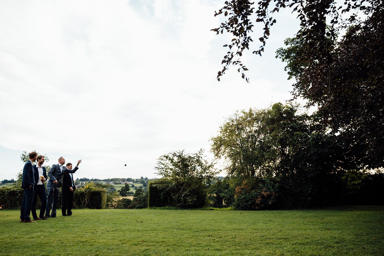 Wedding guests gather on grassy hillside for outdoor celebration photos.