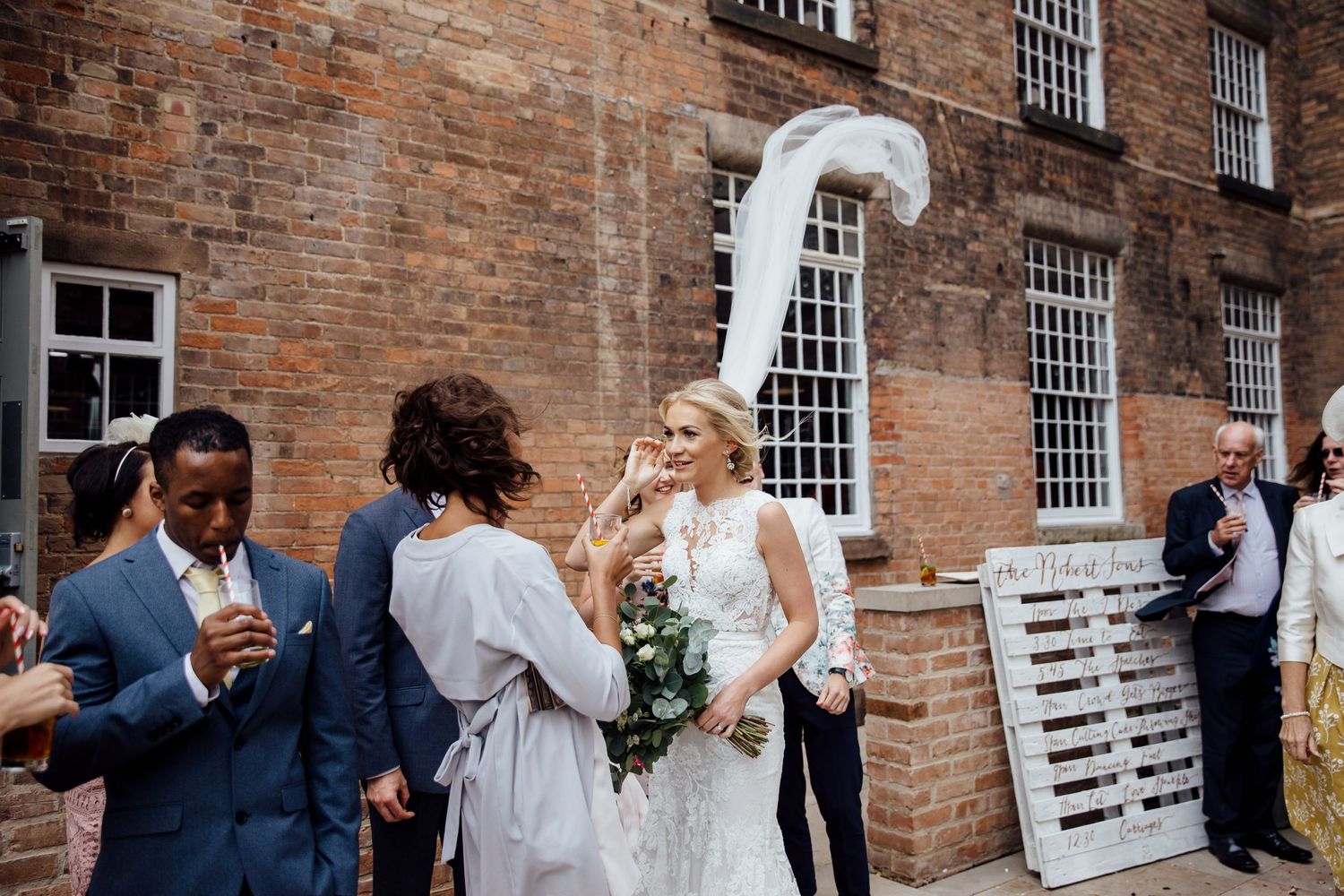 Wedding celebration outside historic brick building with white architectural details.