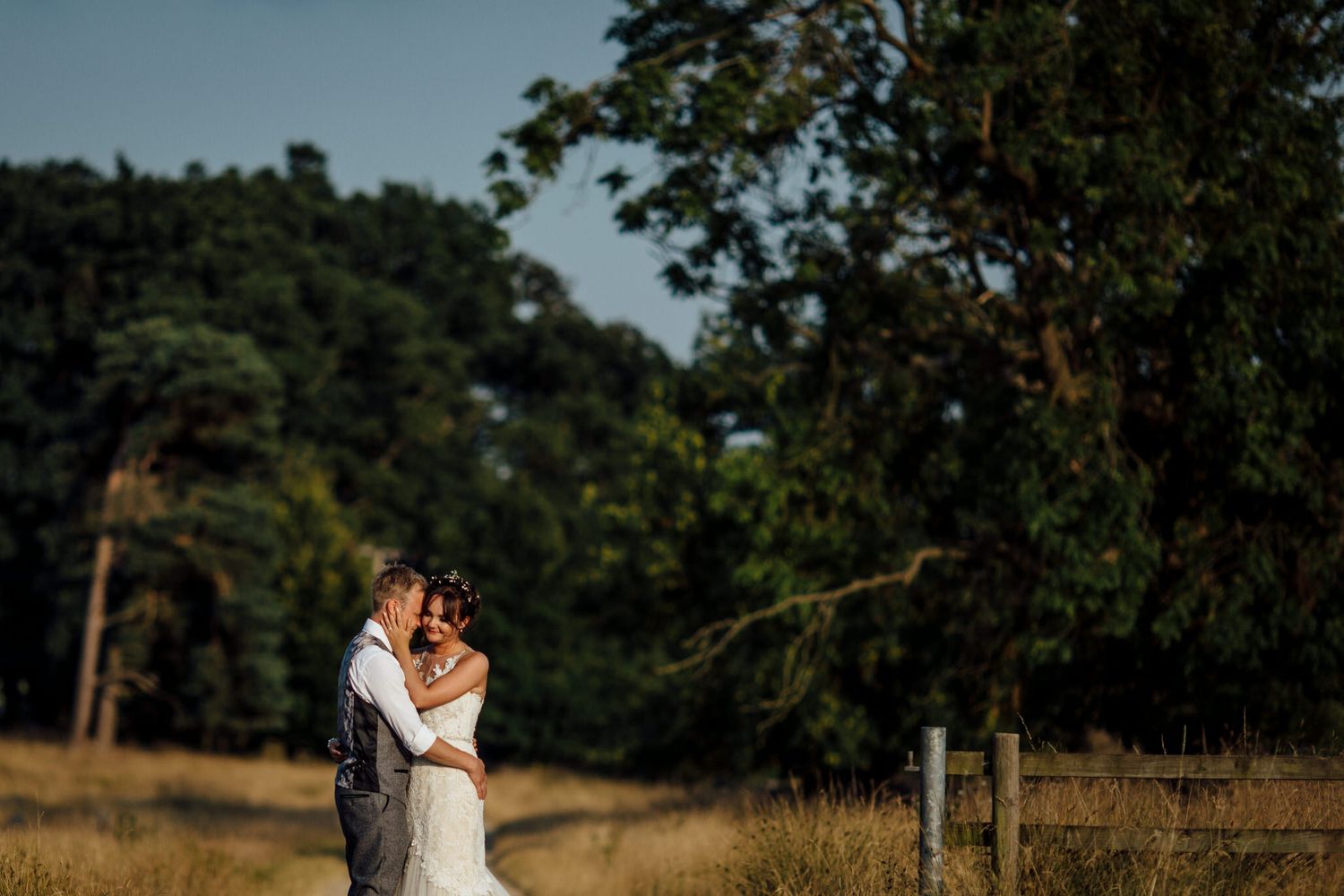 Wedding couple embracing in a scenic field during golden hour.