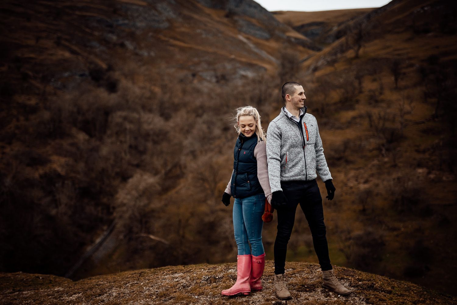 Couple walking along a winding path through brown winter hills.
