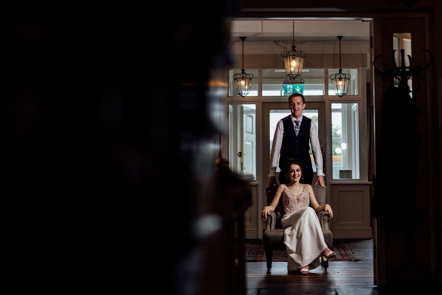 Artistic wedding portrait in an elegant hallway with dramatic lighting and vintage decor.