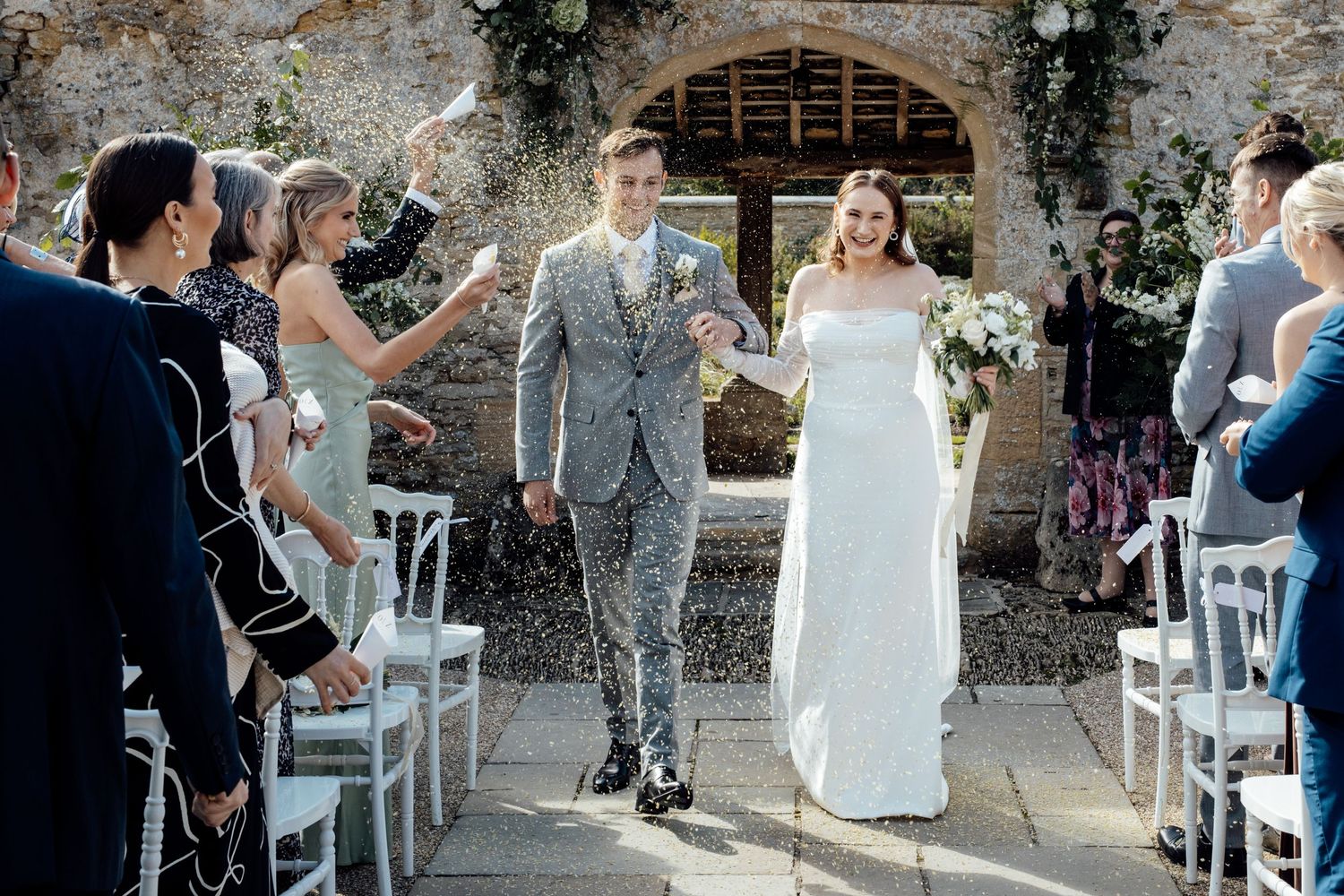 Wedding ceremony setup outdoors with white chairs and floral arch decorations.
