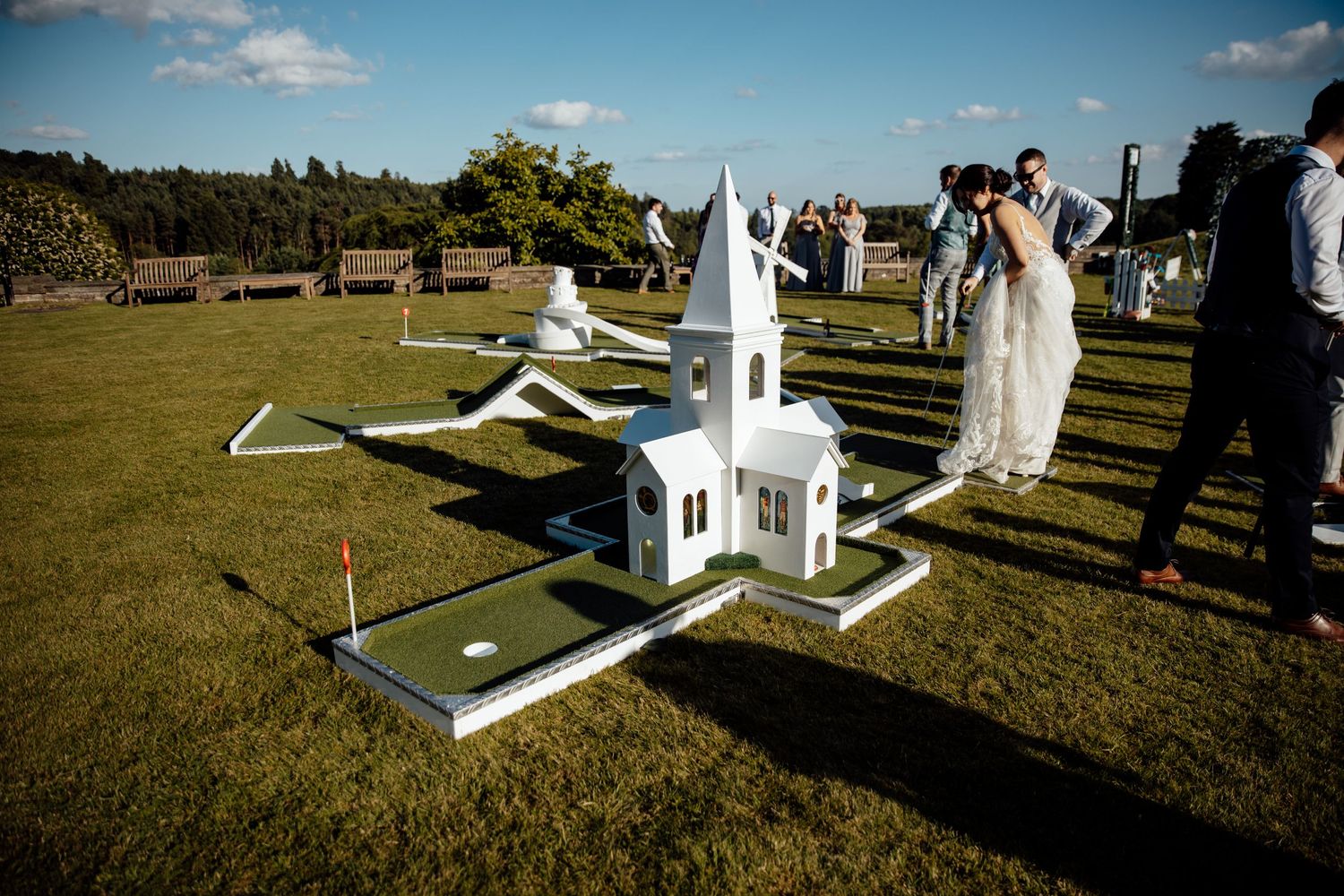 A miniature white church display on grass during an outdoor wedding.