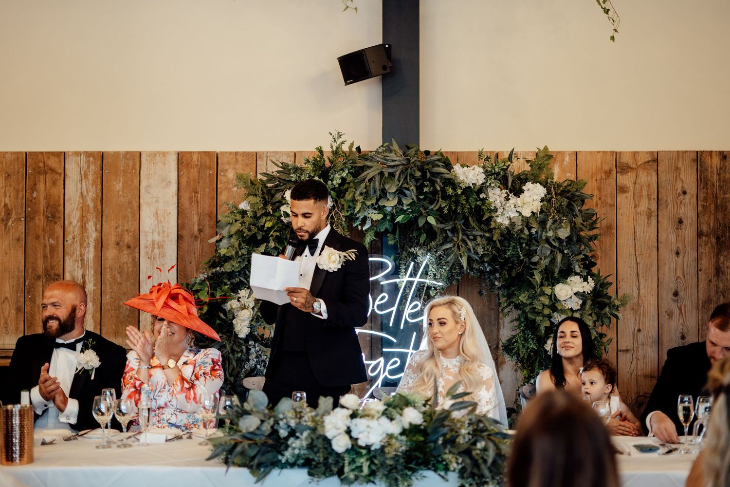 Wedding reception venue decorated with rustic wood panels and floral arrangements.