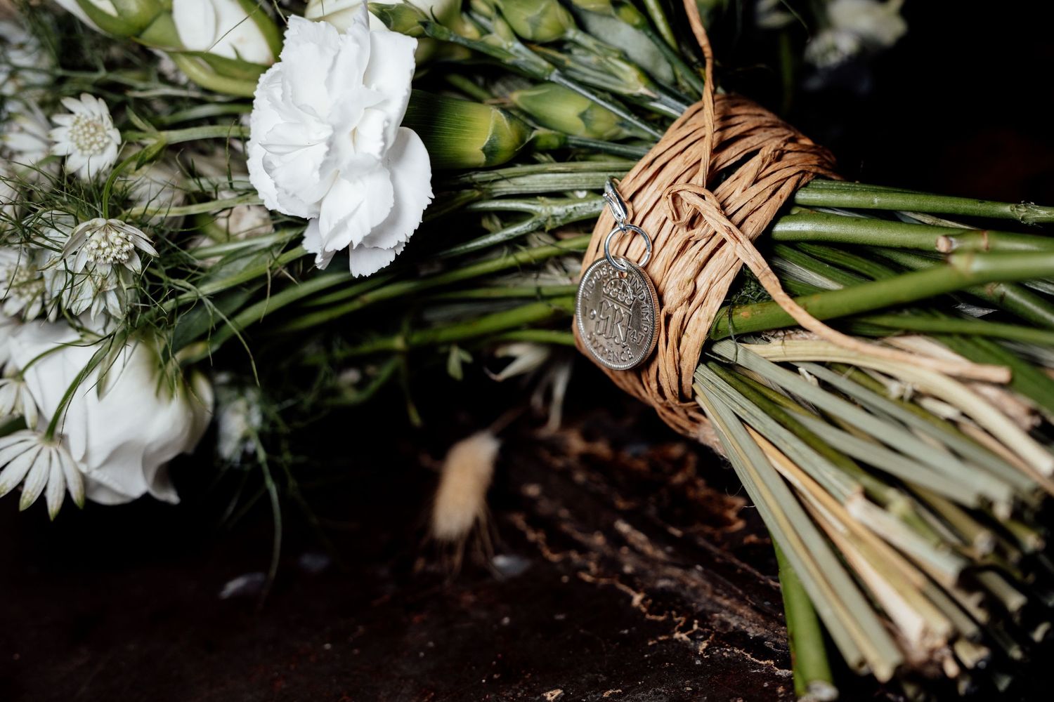 White floral bouquet wrapped in natural twine against dark background.