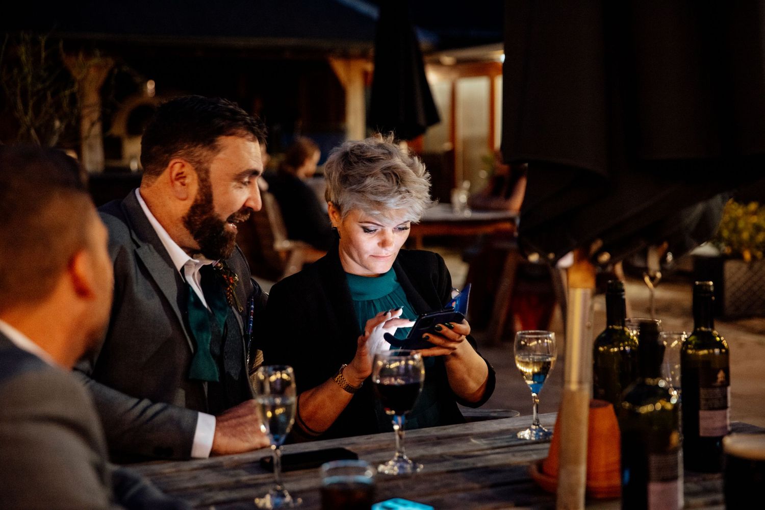 Wedding guests socializing at a dimly lit bar area.