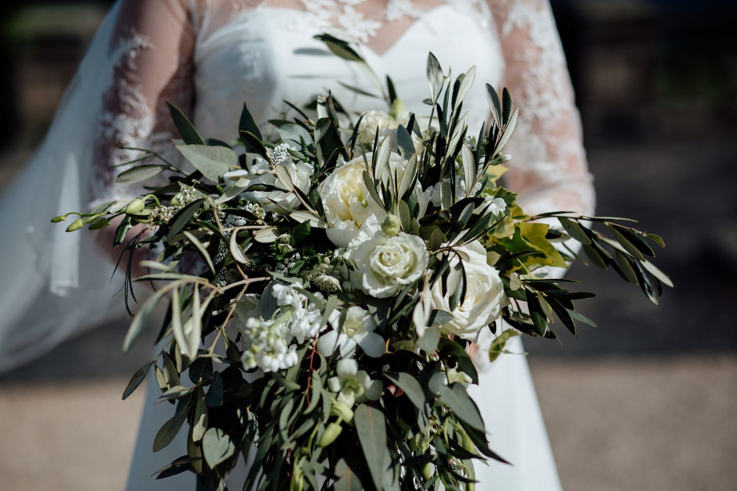 Elegant white and green wedding bouquet with eucalyptus leaves and roses.