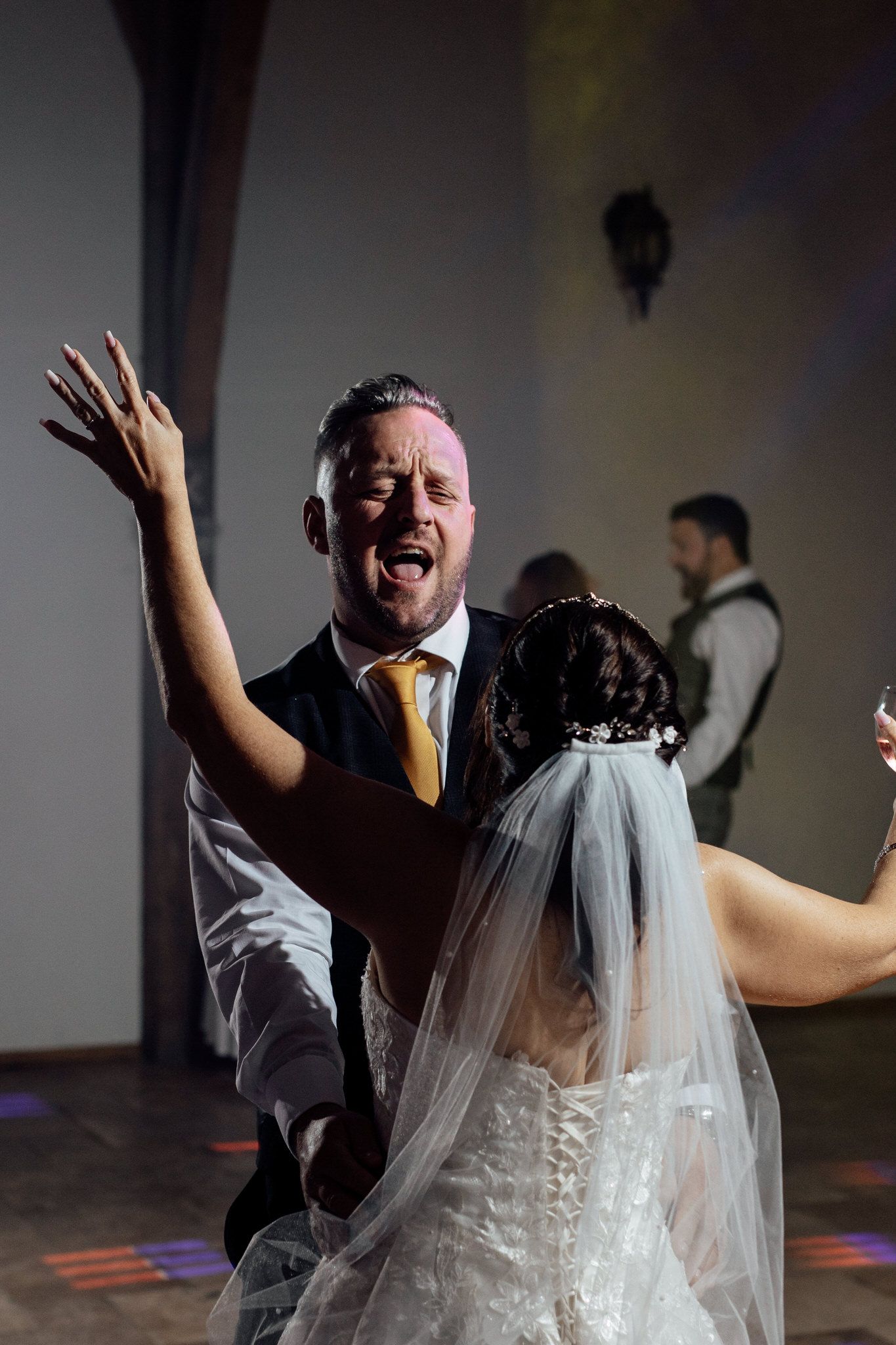 Energetic dance floor celebration with bride in white gown during wedding reception.