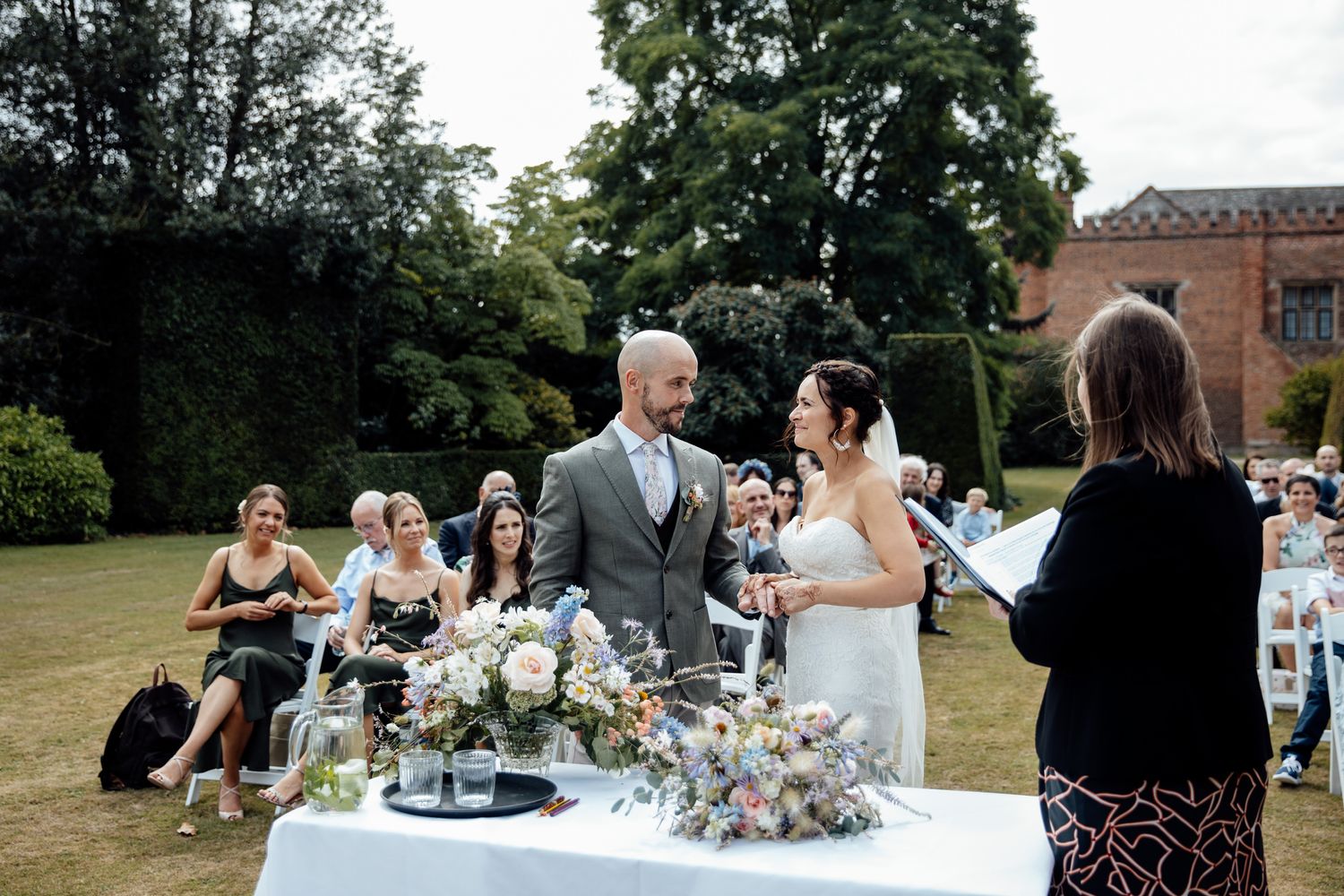 Wedding guests enjoy an elegant outdoor reception with table settings and floral arrangements.